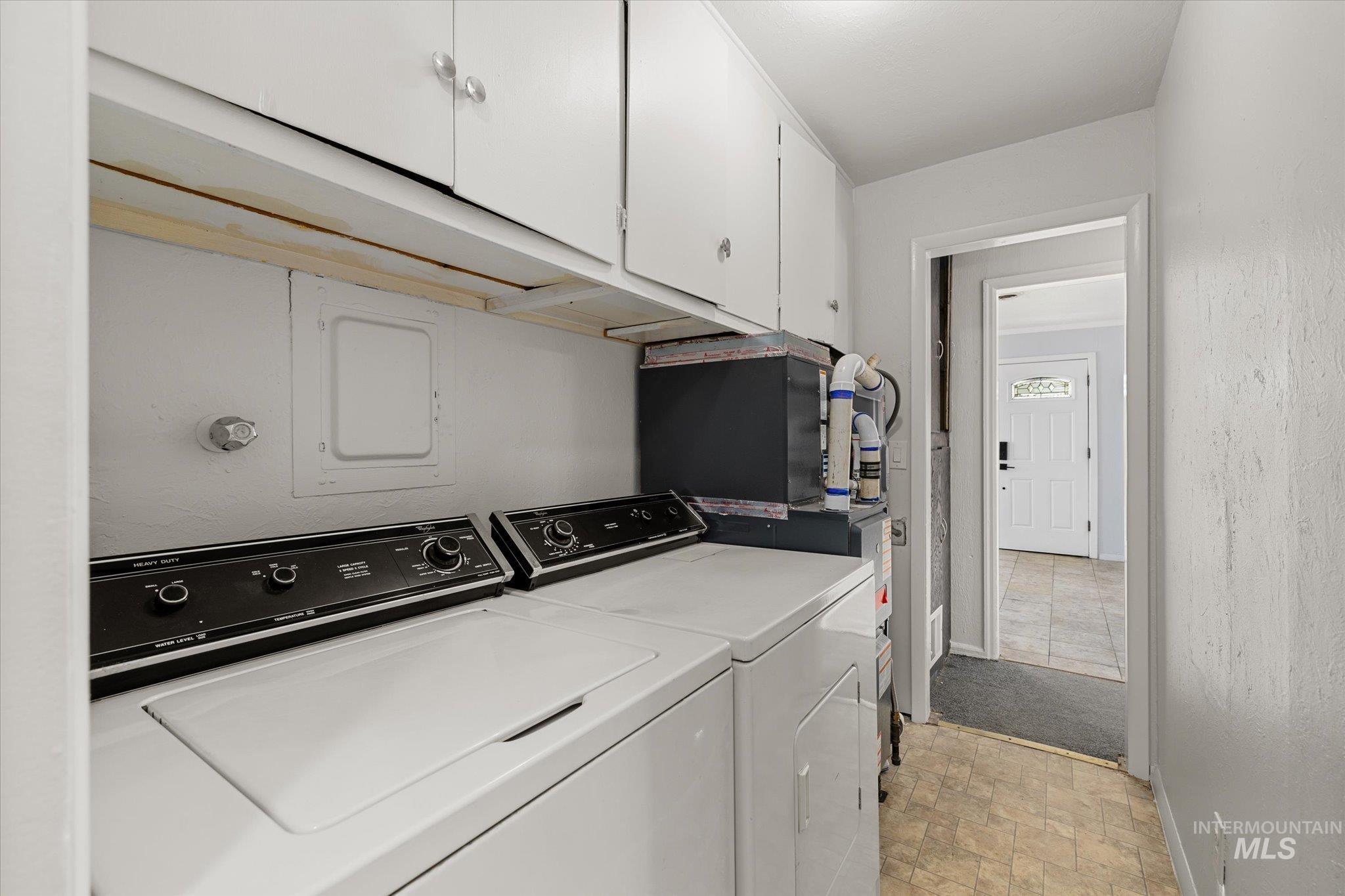 Laundry room featuring cabinet space, washing machine and dryer, and light stone finish floors
