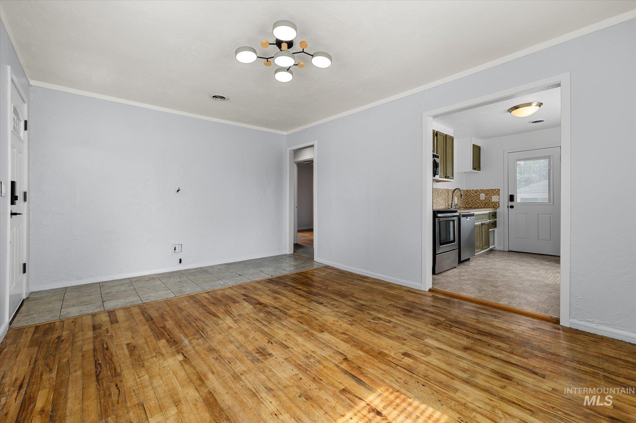 Unfurnished living room featuring ornamental molding, light wood finished floors, and a chandelier