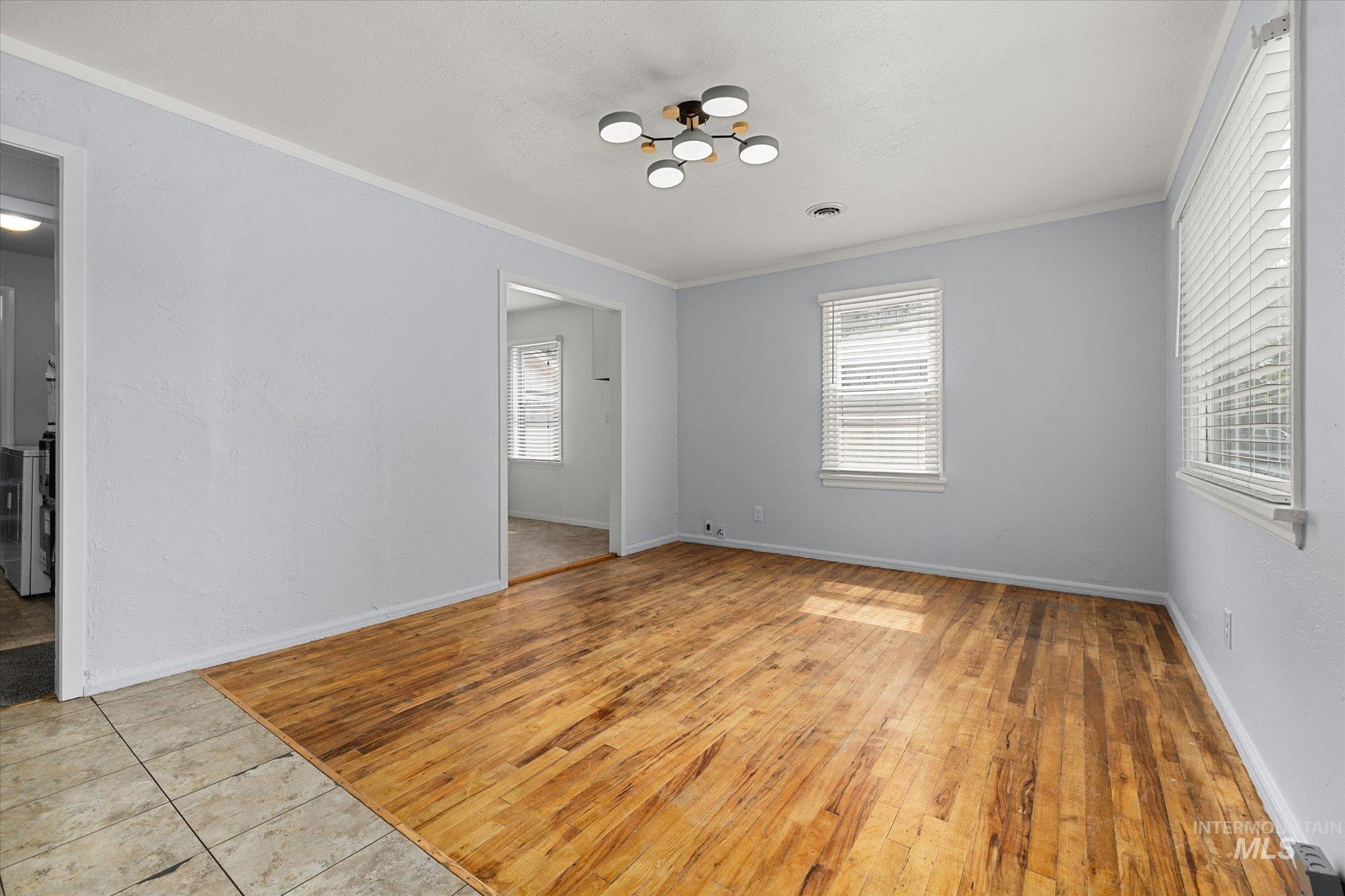 Unfurnished room with ornamental molding, light wood-type flooring, and a chandelier