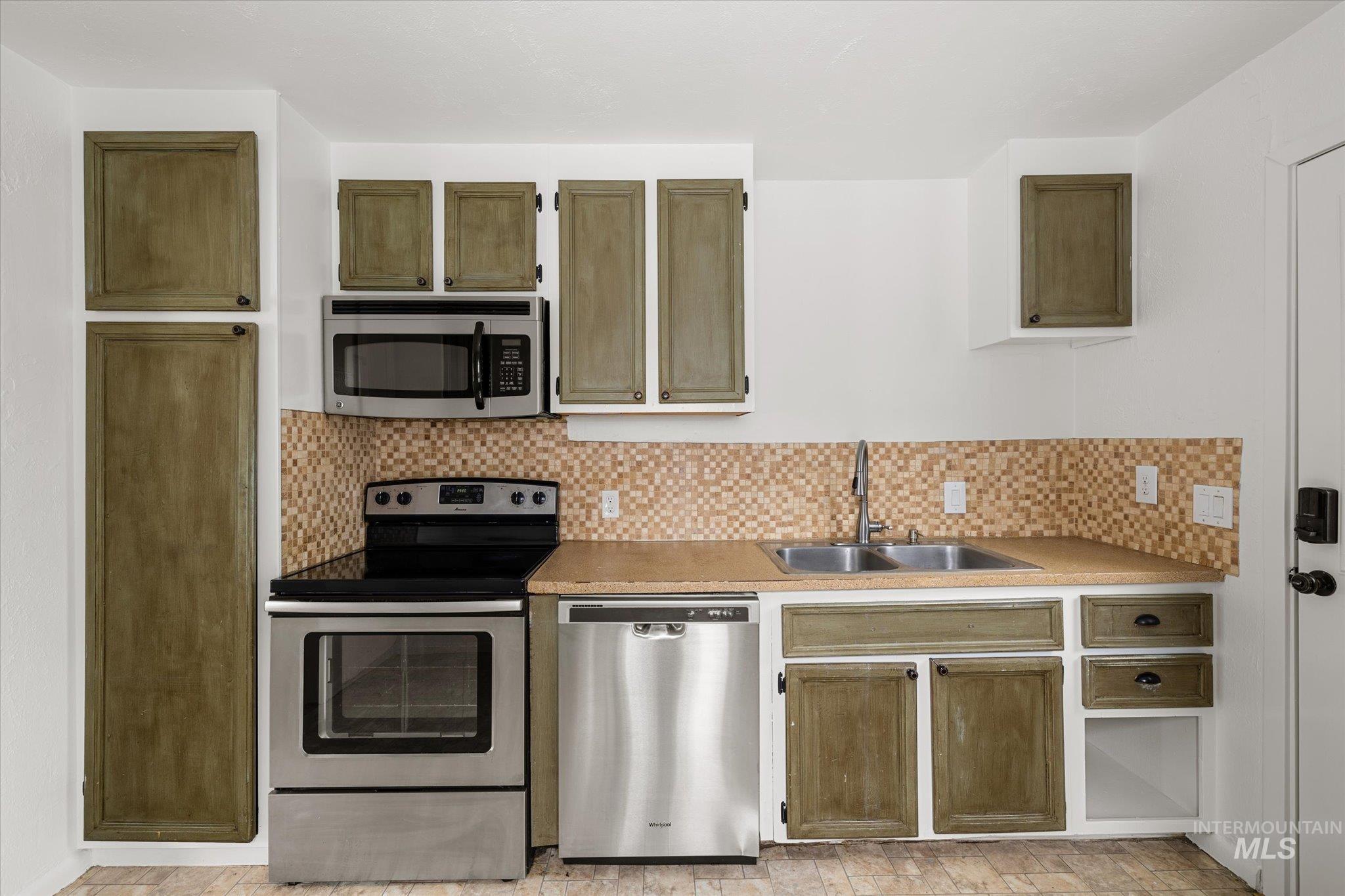 Kitchen featuring stainless steel appliances, light countertops, and tasteful backsplash