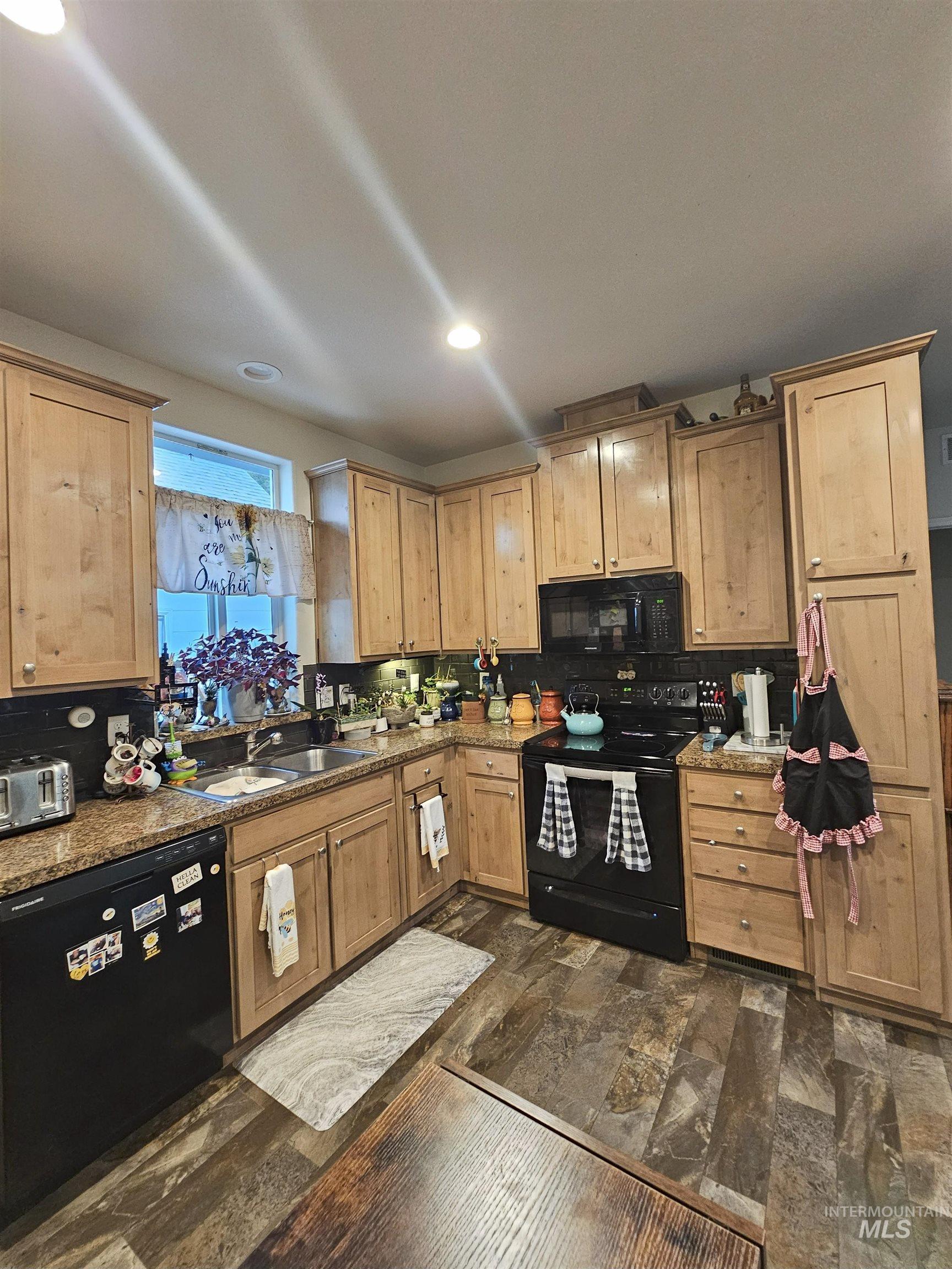 Kitchen with black appliances, light stone counters, recessed lighting, and light brown cabinetry