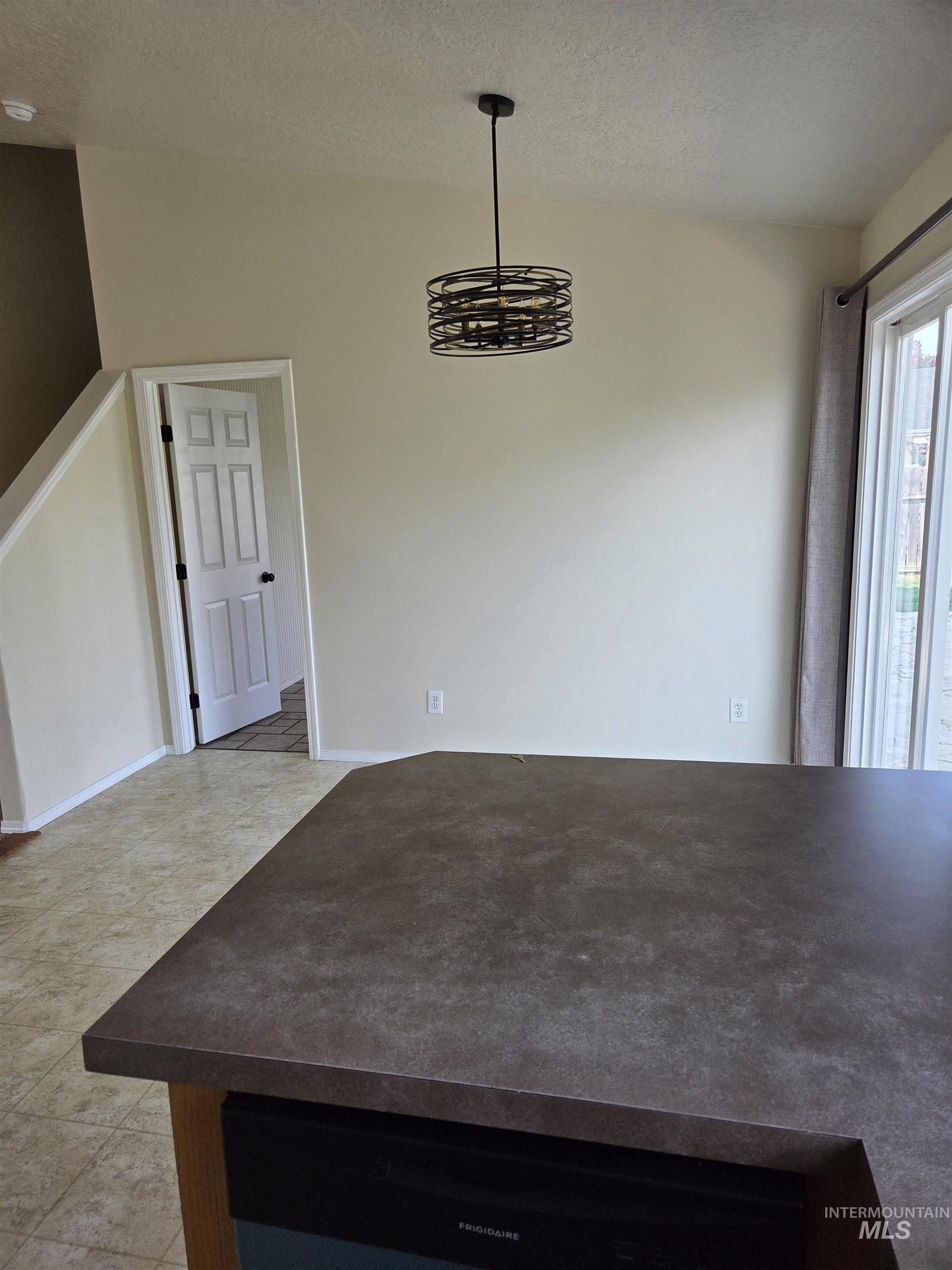 Unfurnished dining area with a textured ceiling and light tile patterned flooring