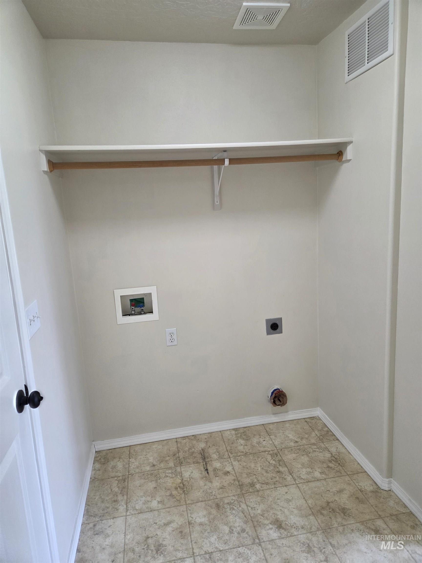Laundry room with hookup for a washing machine, electric dryer hookup, and light tile patterned floors