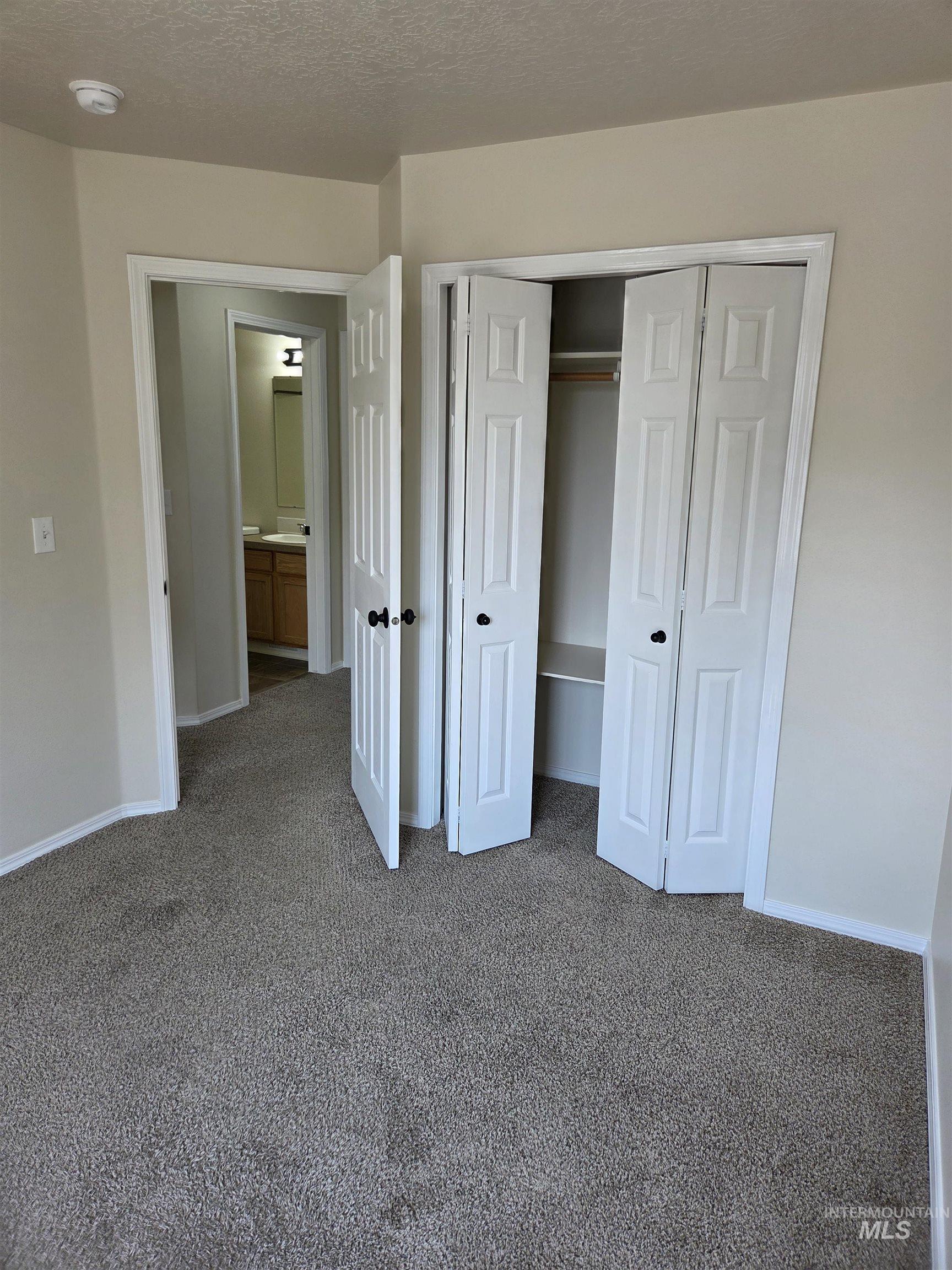 Unfurnished bedroom with carpet, a closet, and a textured ceiling