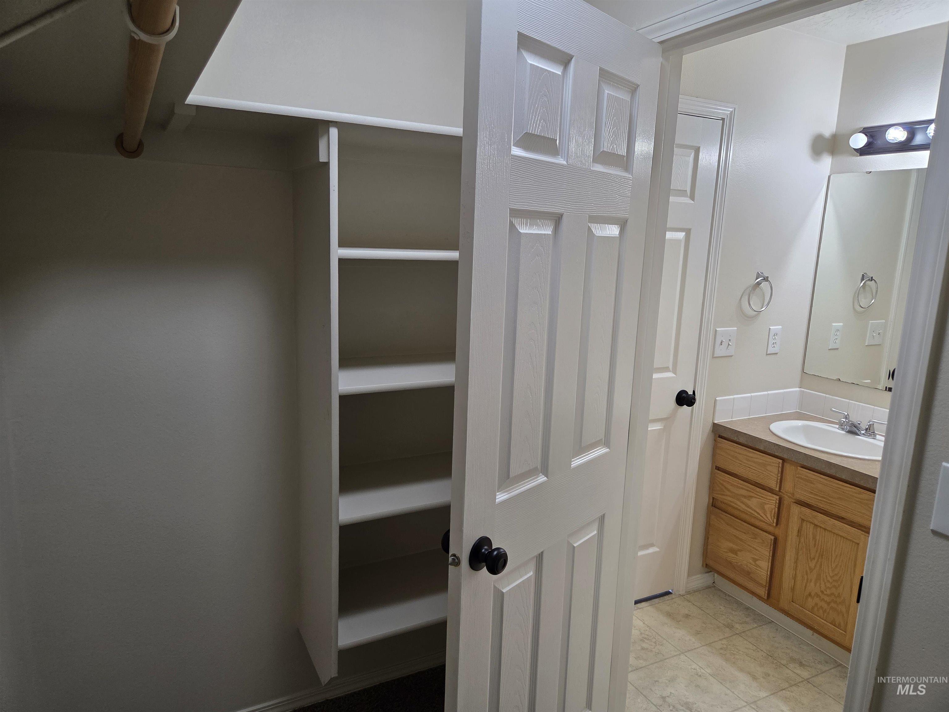 Bathroom featuring vanity, light tile patterned floors, and a closet