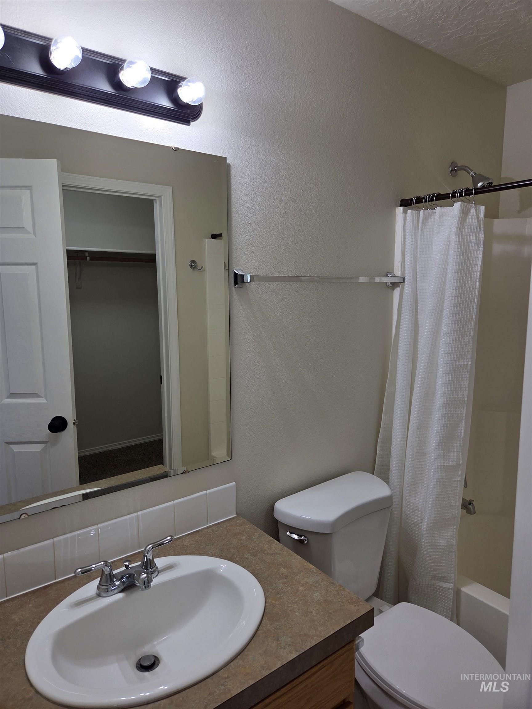 Full bath with shower / tub combo, vanity, and a closet