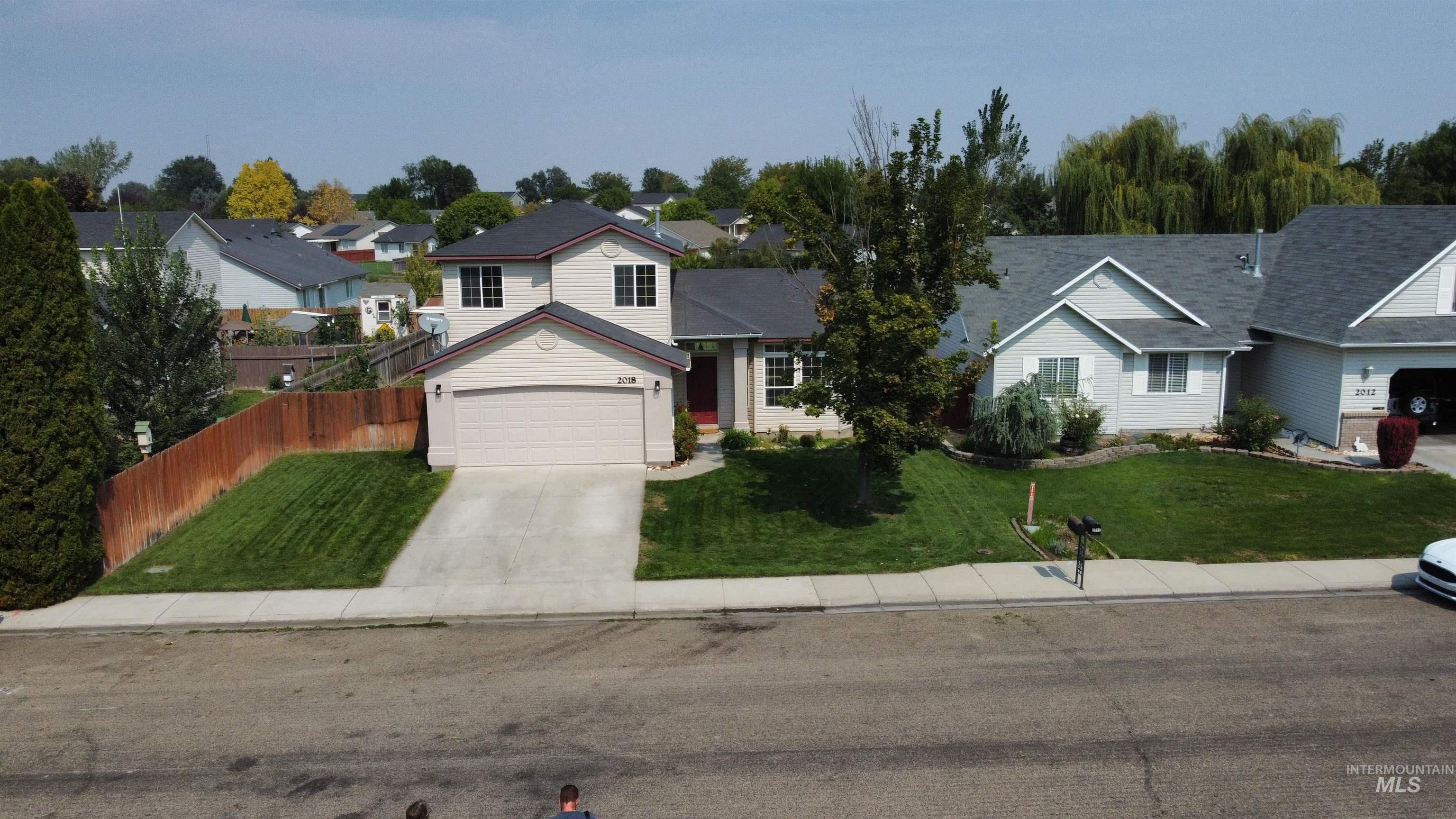 Traditional-style house with driveway, a residential view, and an attached garage