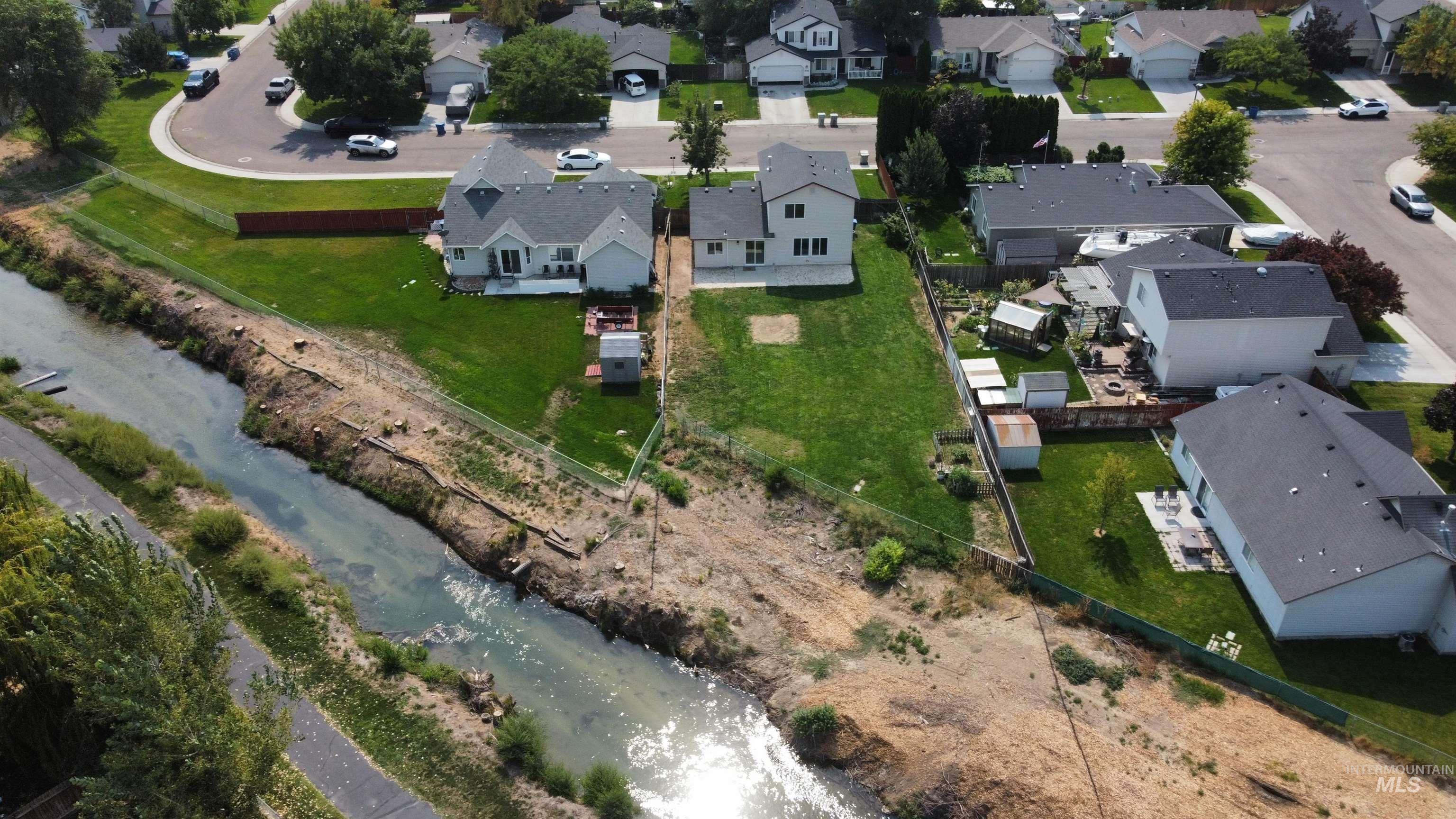Aerial view of property and surrounding area featuring nearby suburban area and a nearby body of water