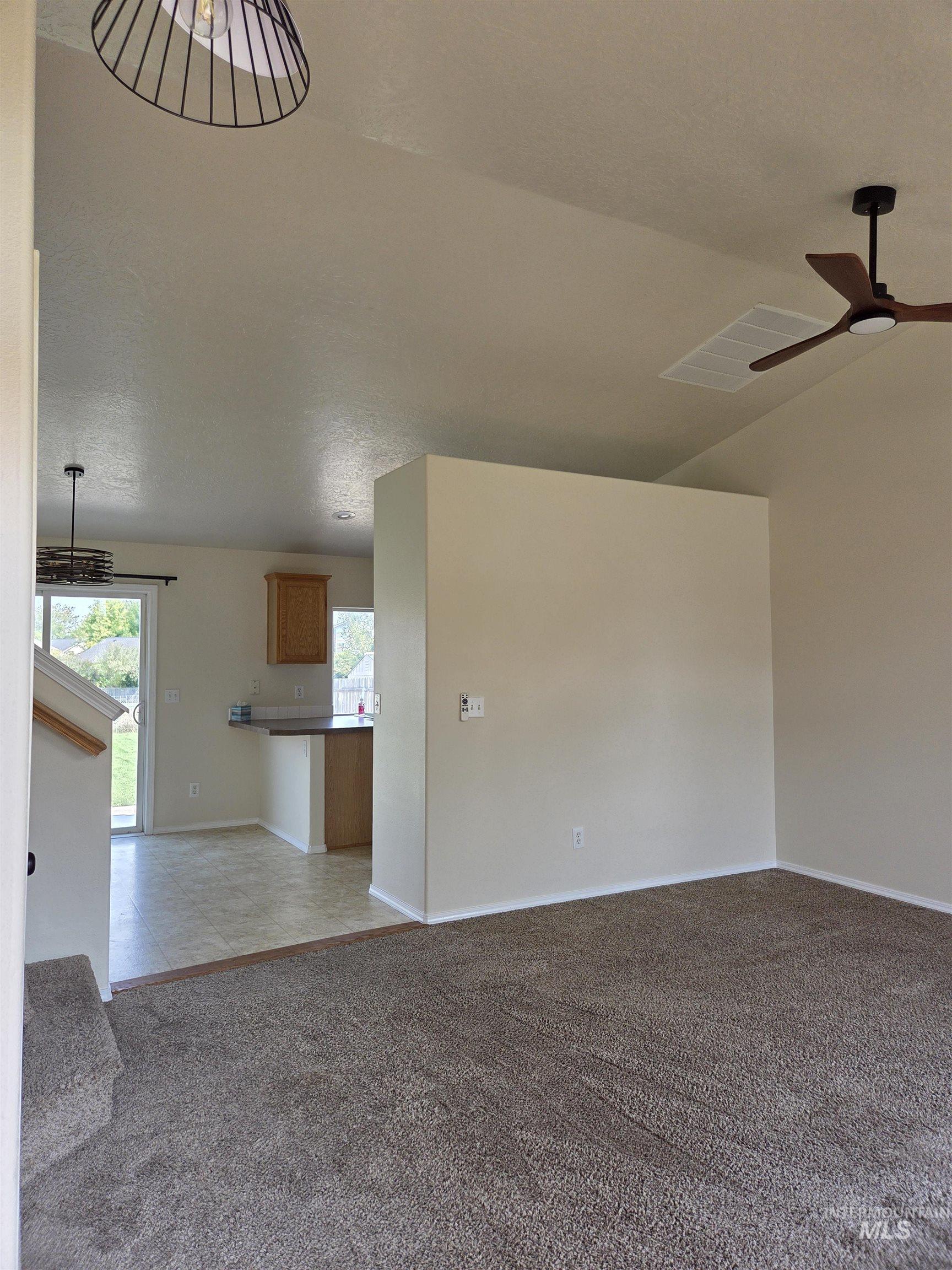 Empty room with light carpet, lofted ceiling, a ceiling fan, light tile patterned floors, and a textured ceiling