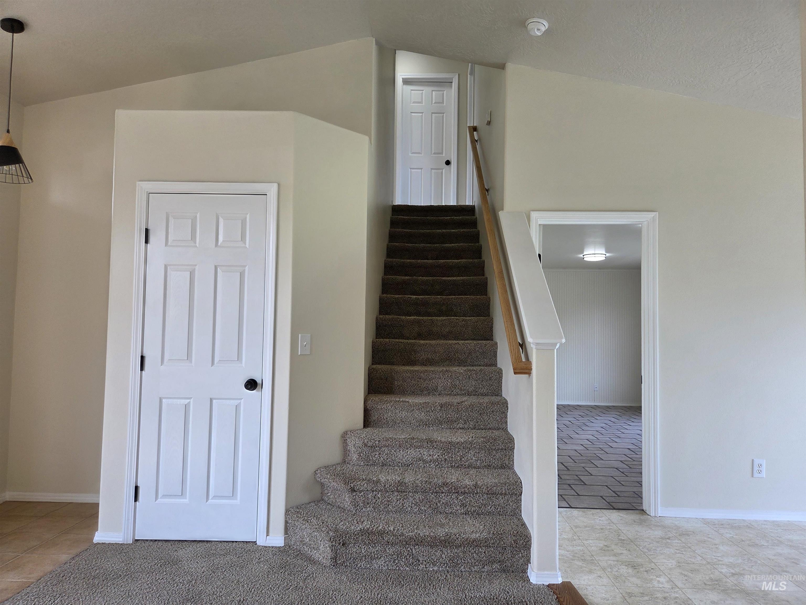 Stairway with tile patterned floors and baseboards