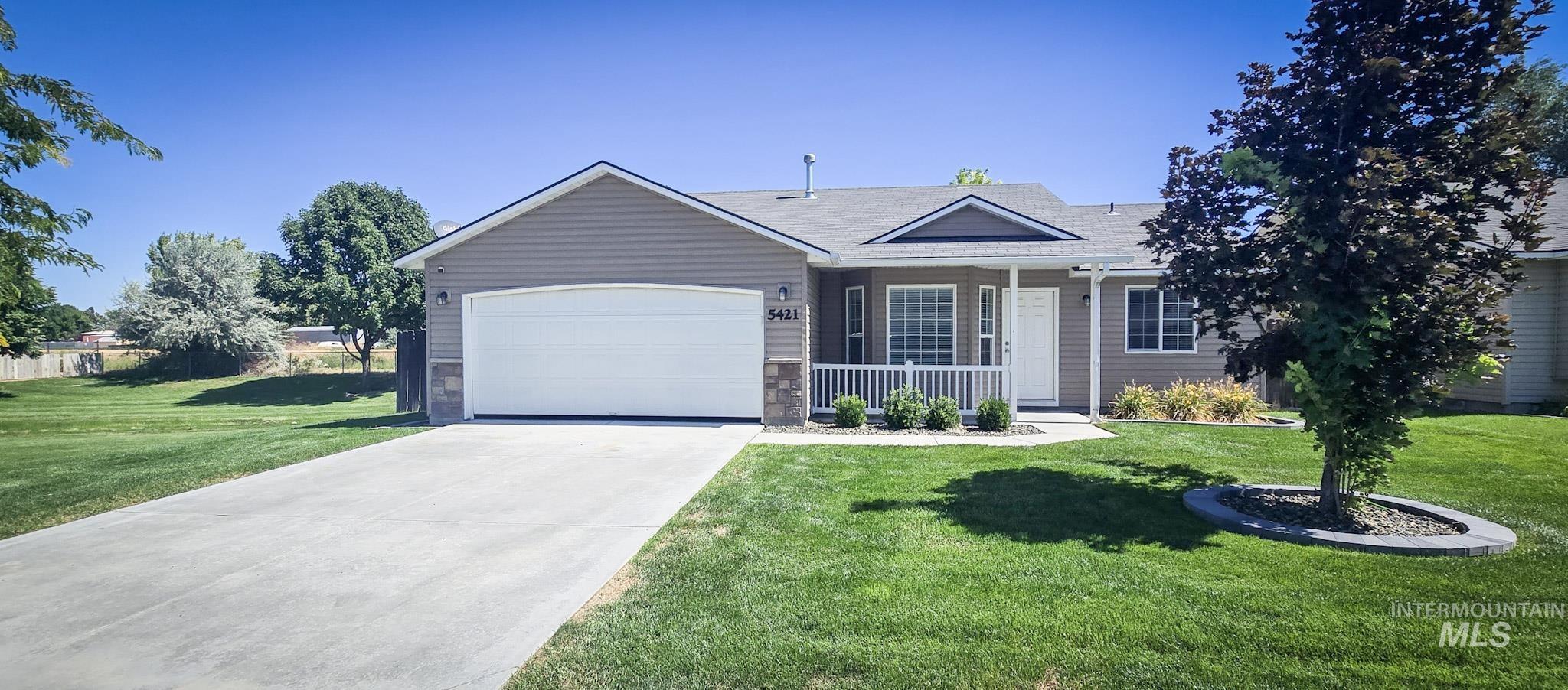 Ranch-style home with covered porch, concrete driveway, a front yard, and a garage
