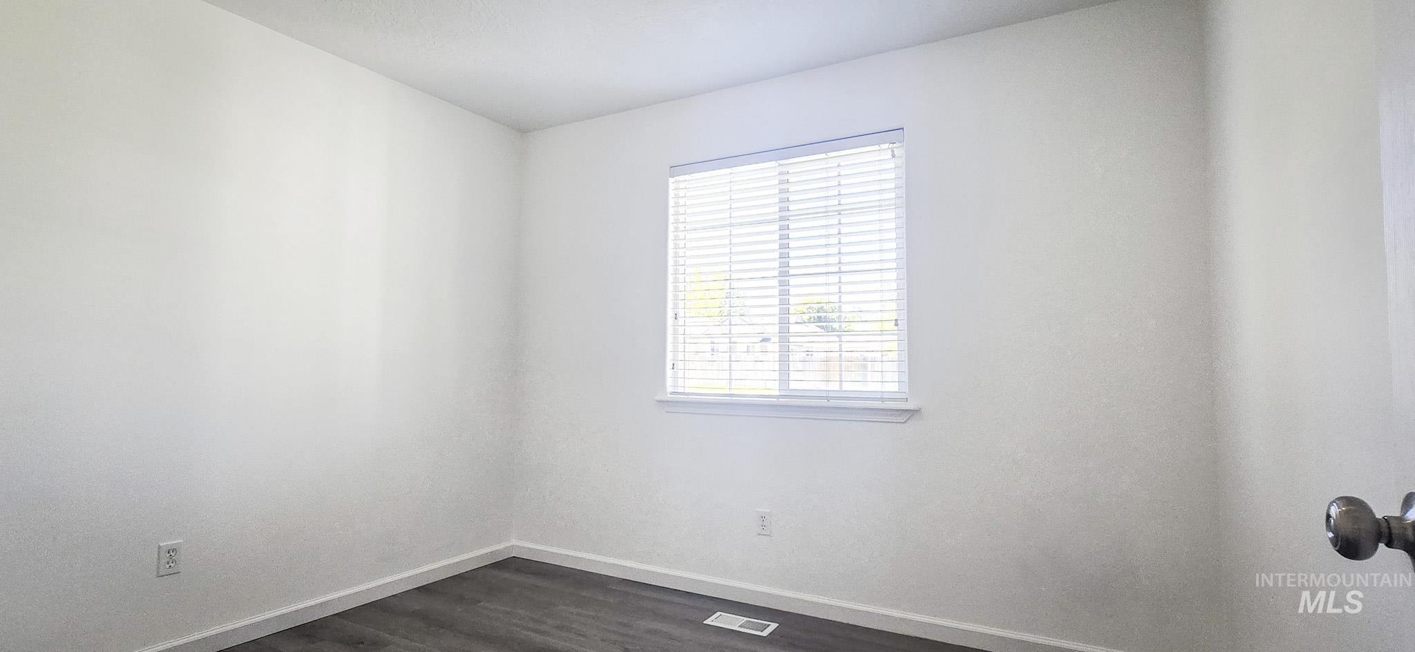 Unfurnished room featuring baseboards and dark wood finished floors