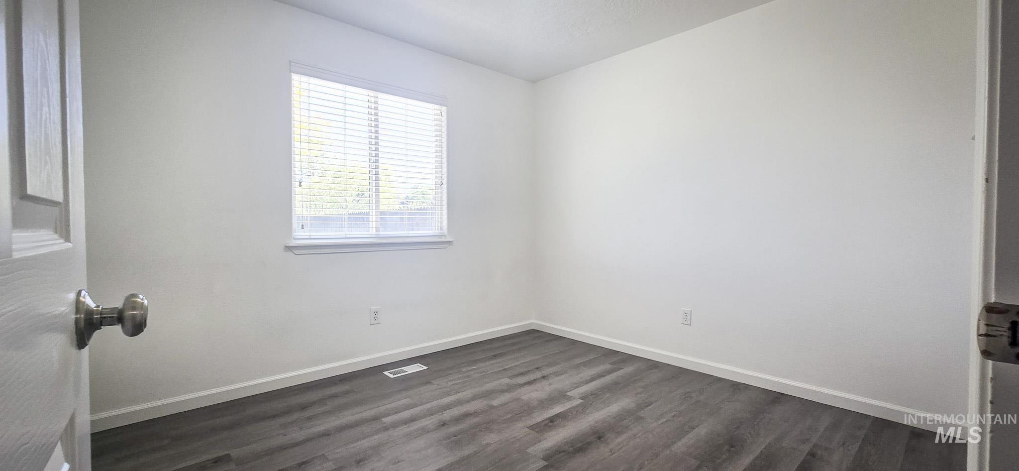 Unfurnished bedroom featuring dark wood finished floors and baseboards