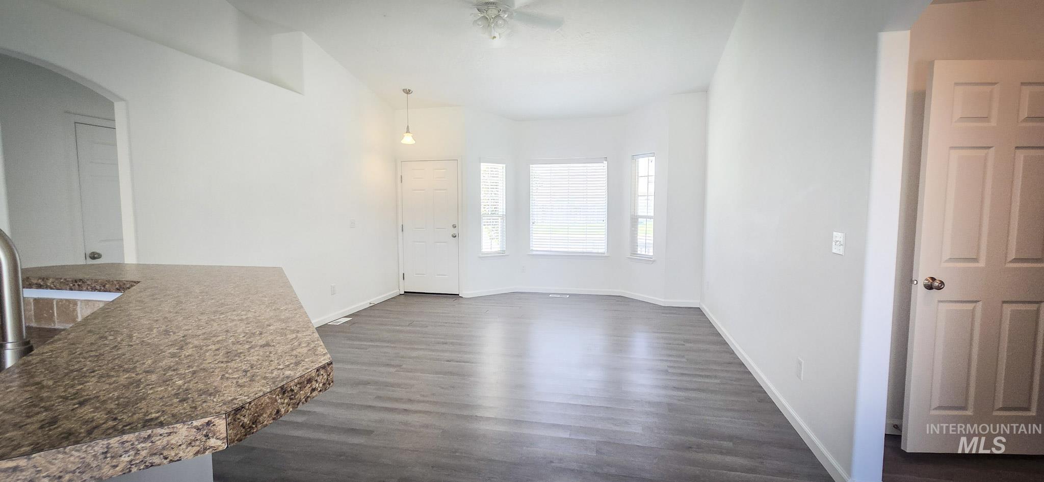 Unfurnished dining area featuring arched walkways, dark wood-type flooring, and ceiling fan