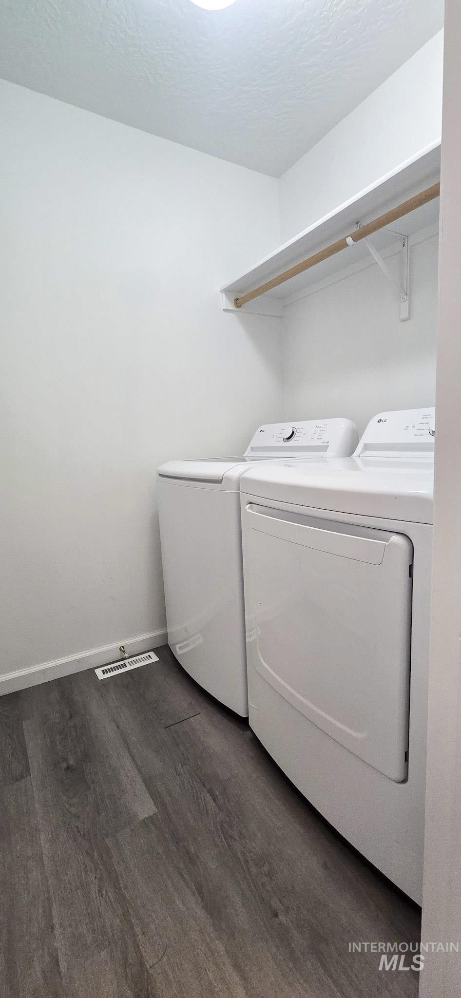 Washroom with dark wood-style floors, independent washer and dryer, and a textured ceiling