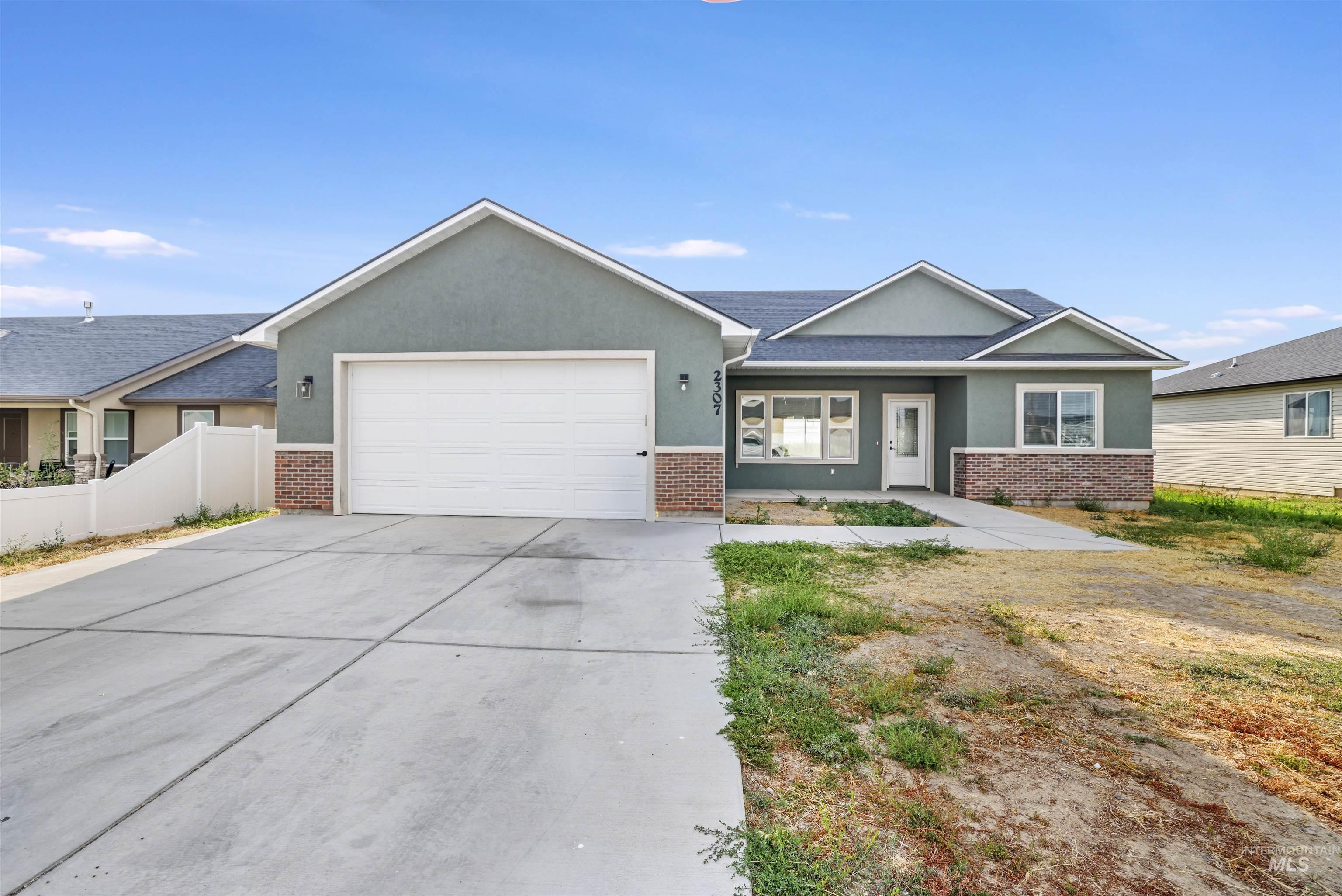 View of front of property with brick siding, stucco siding, concrete driveway, and a garage