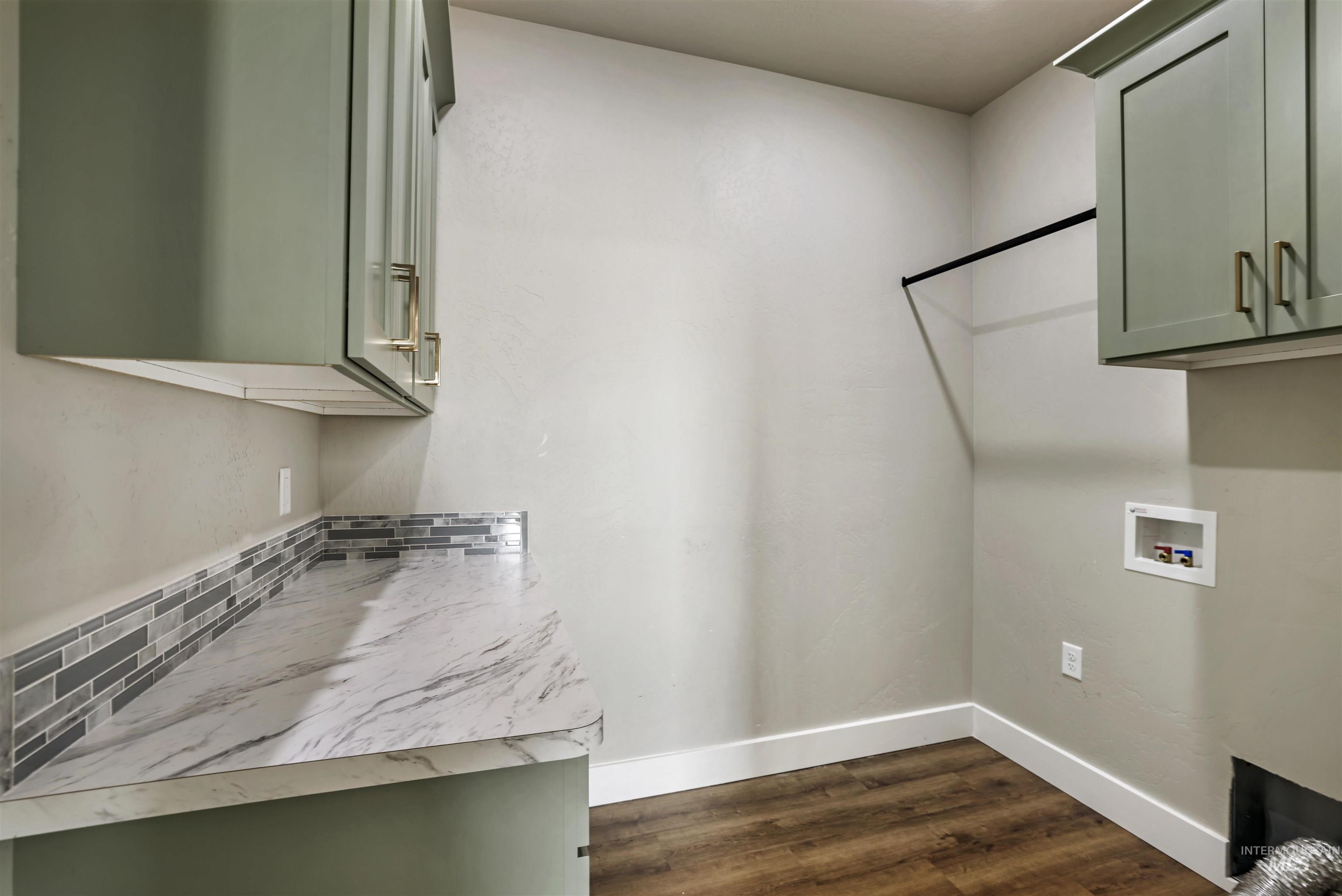 Laundry room featuring dark wood-type flooring, cabinet space, and washer hookup