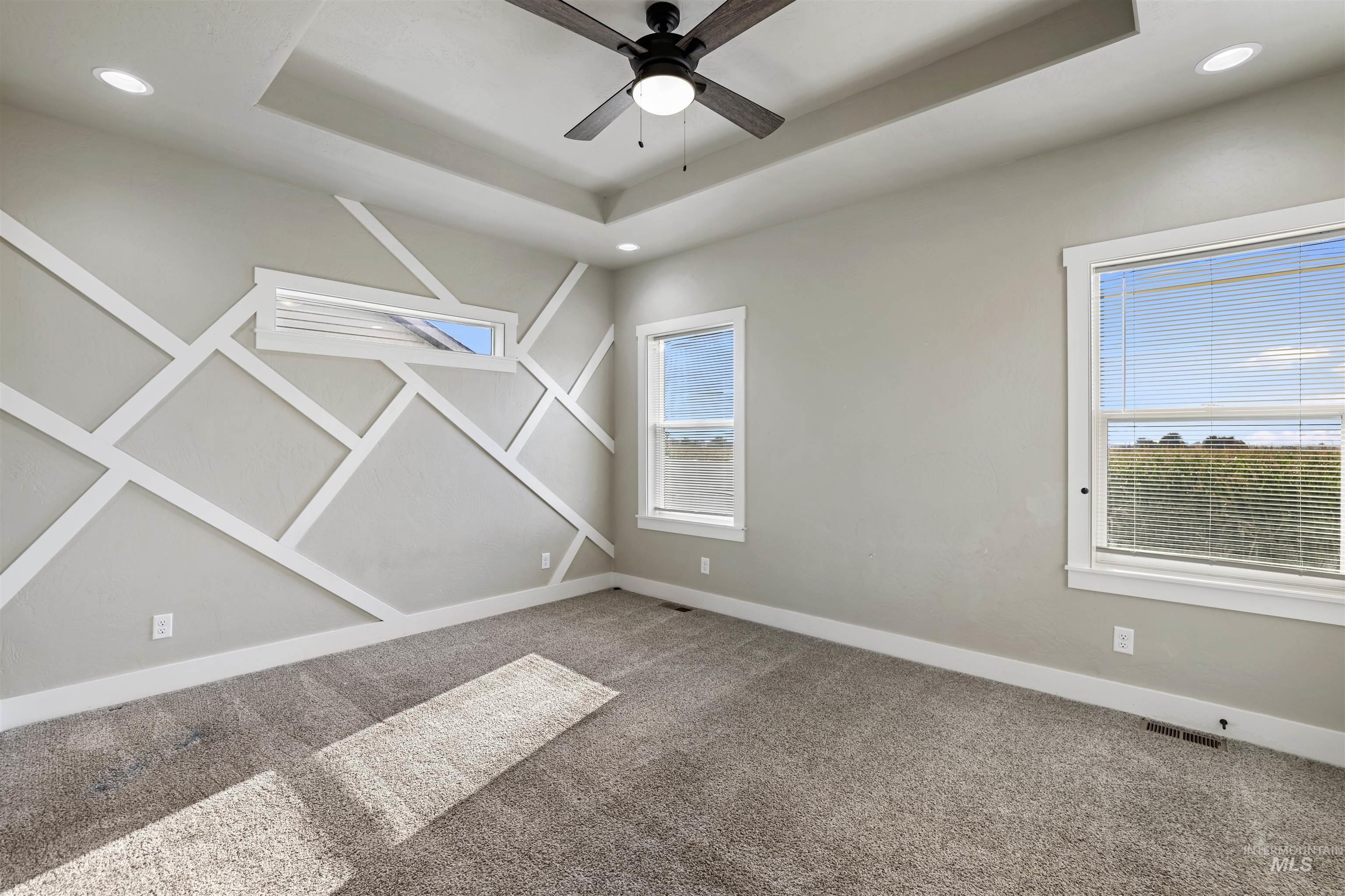 Carpeted spare room with a raised ceiling, recessed lighting, and ceiling fan