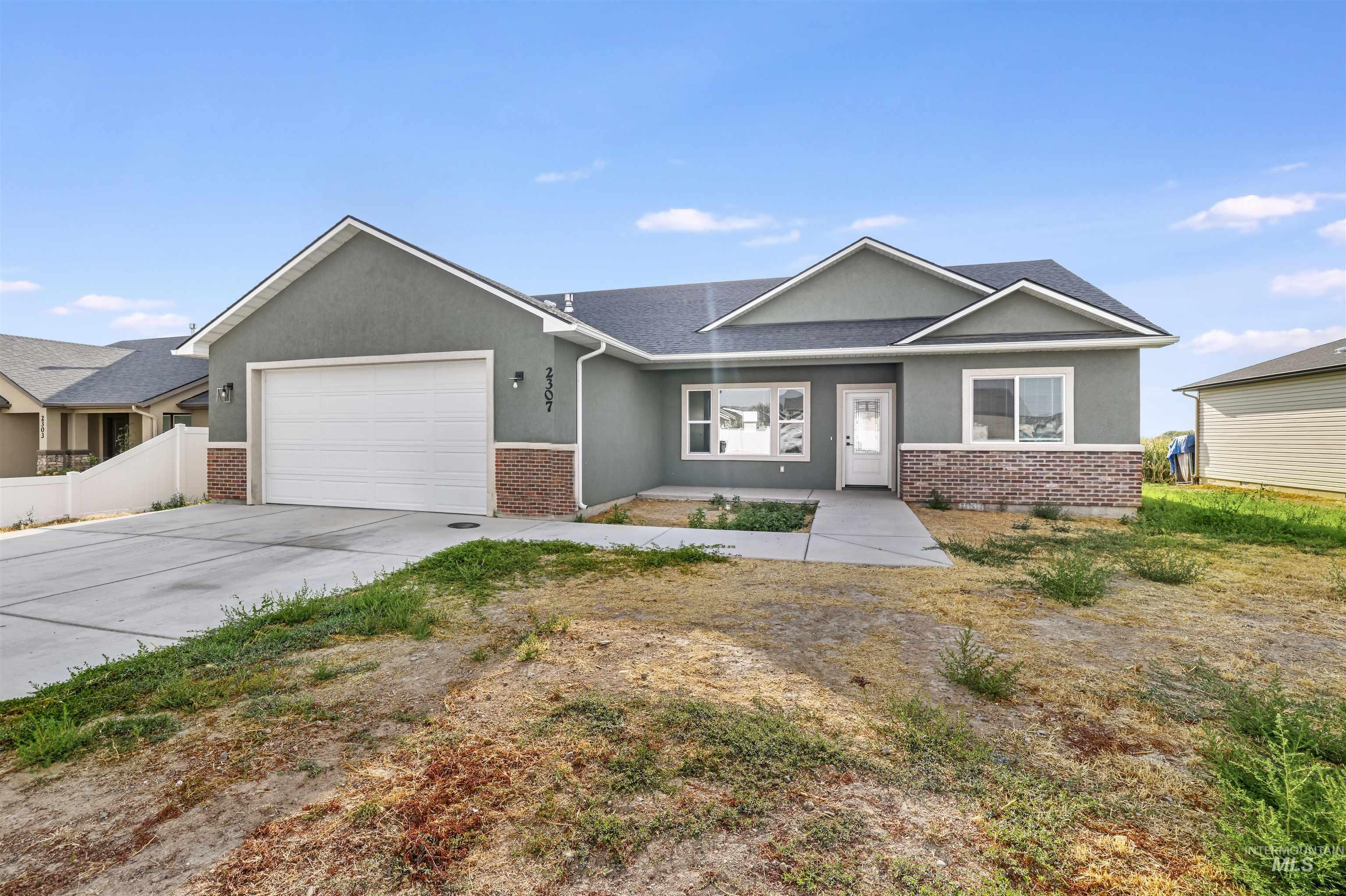 View of front facade with stucco siding, brick siding, driveway, and an attached garage