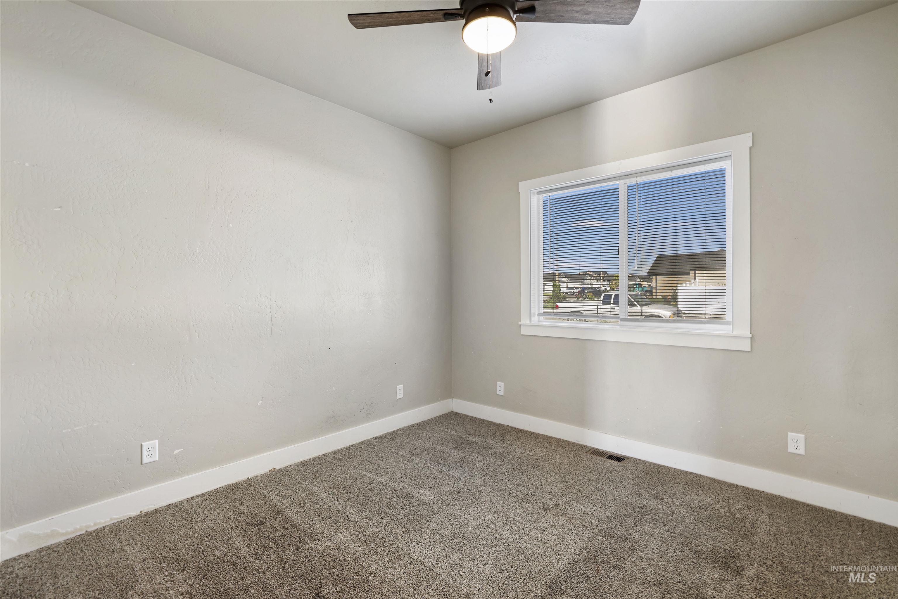 Carpeted empty room with baseboards and a ceiling fan