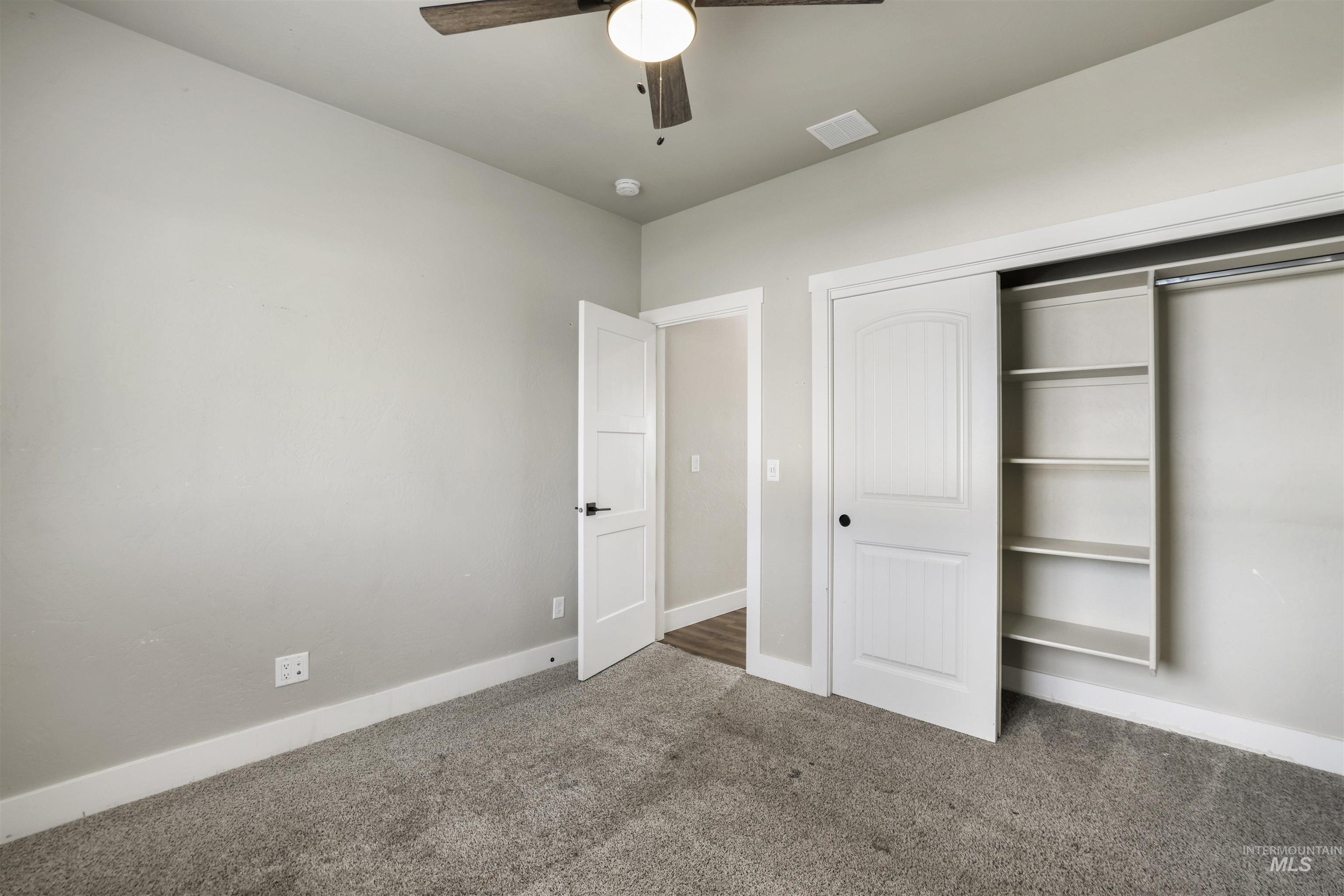 Unfurnished bedroom featuring dark carpet, a closet, and ceiling fan