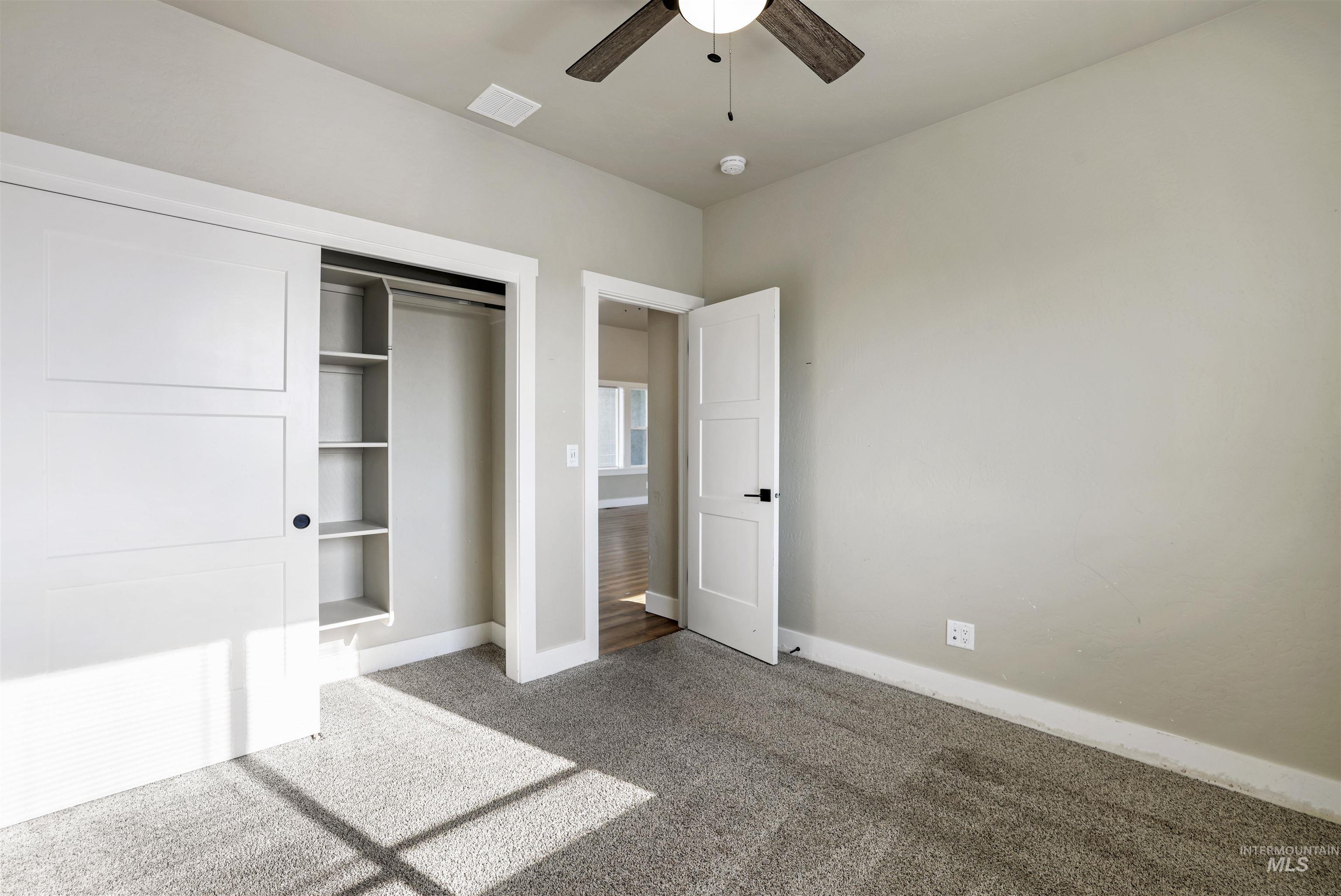 Unfurnished bedroom featuring carpet flooring, a closet, and a ceiling fan