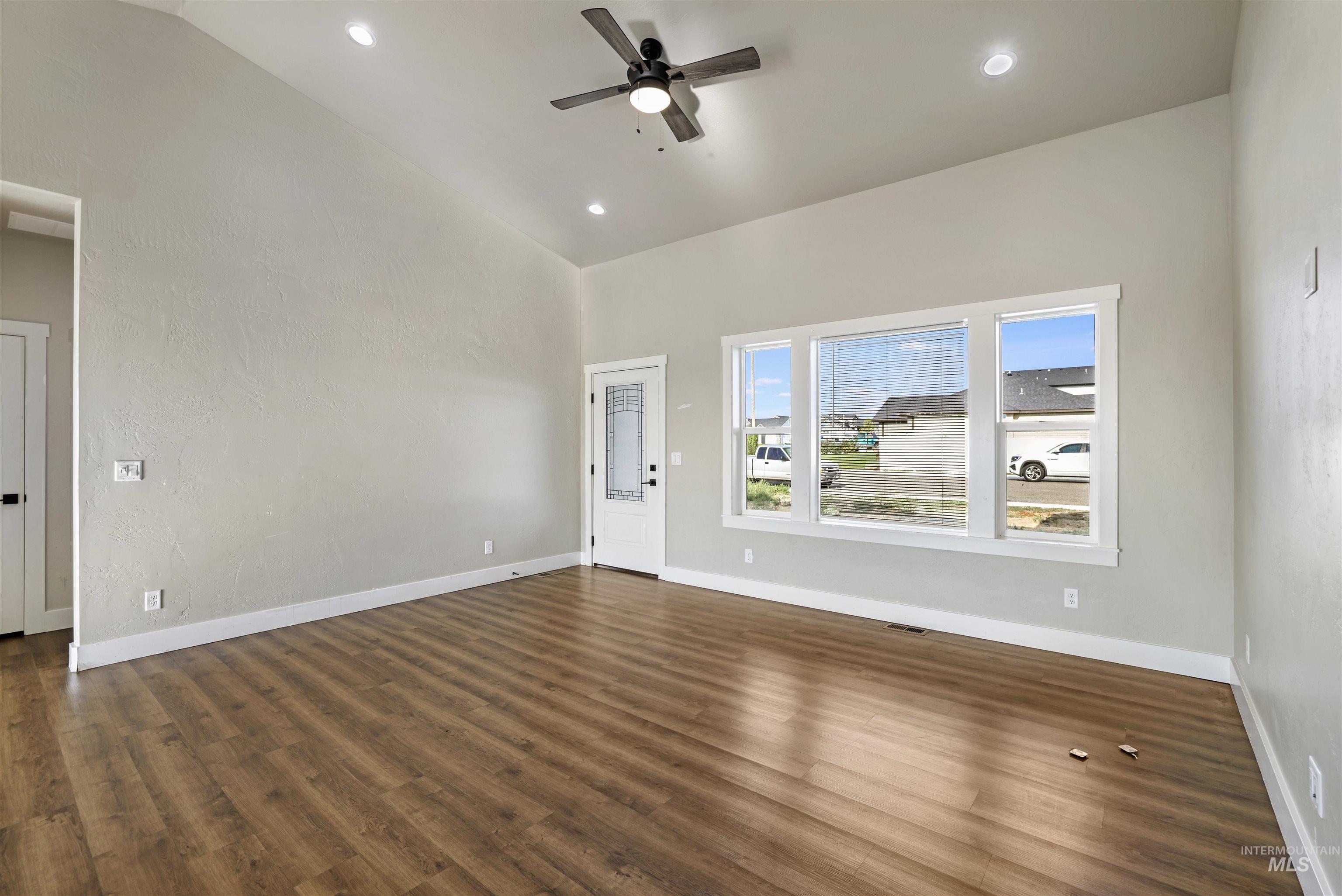 Unfurnished living room featuring a ceiling fan, dark wood-style flooring, recessed lighting, and high vaulted ceiling