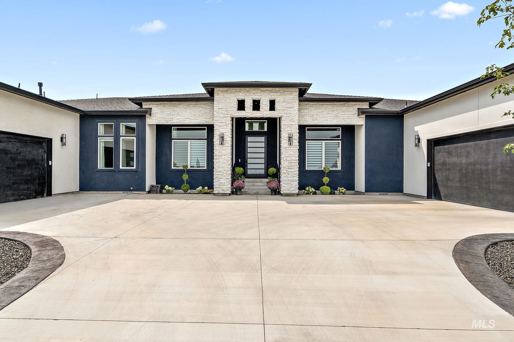Prairie-style house featuring a garage, stone siding, stucco siding, and driveway