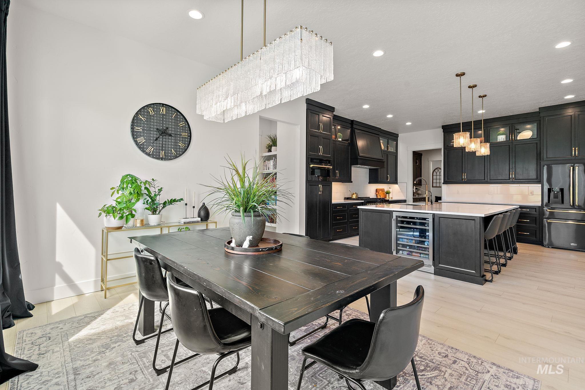 Dining room with recessed lighting, beverage cooler, light wood finished floors, and a chandelier