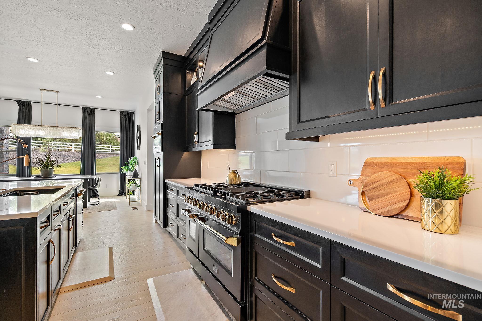 Kitchen featuring double oven range, hanging light fixtures, custom range hood, recessed lighting, and light stone countertops