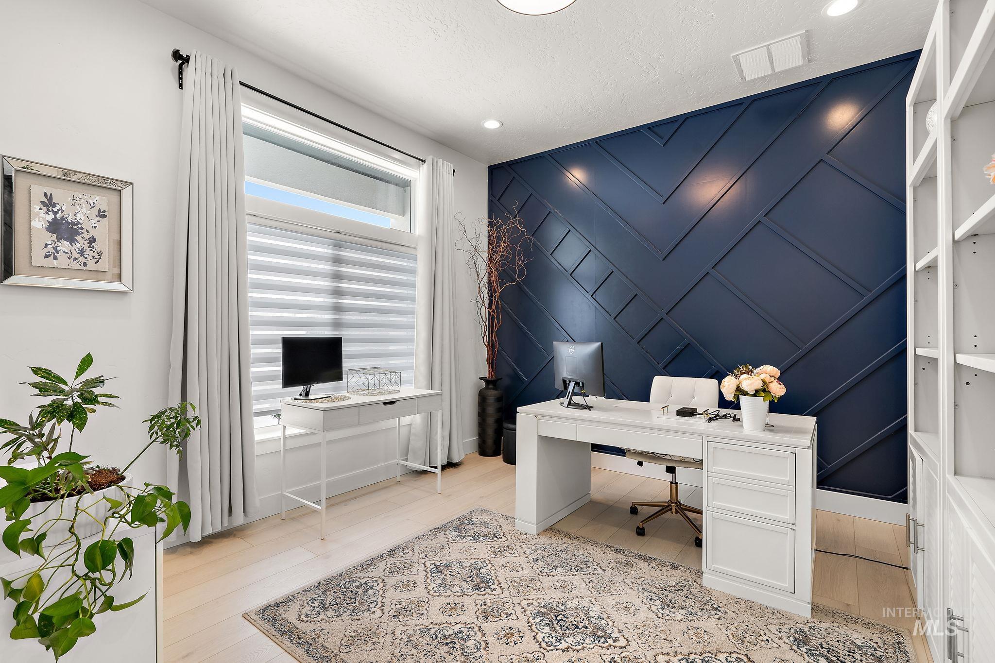 Home office featuring an accent wall, light wood-style floors, a decorative wall, a textured ceiling, and recessed lighting