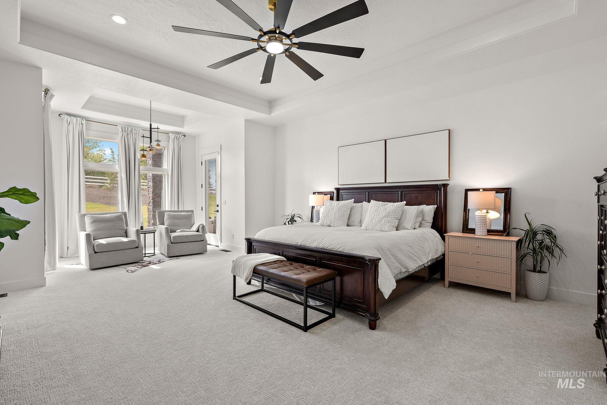 Bedroom featuring a raised ceiling, access to outside, carpet flooring, and a ceiling fan