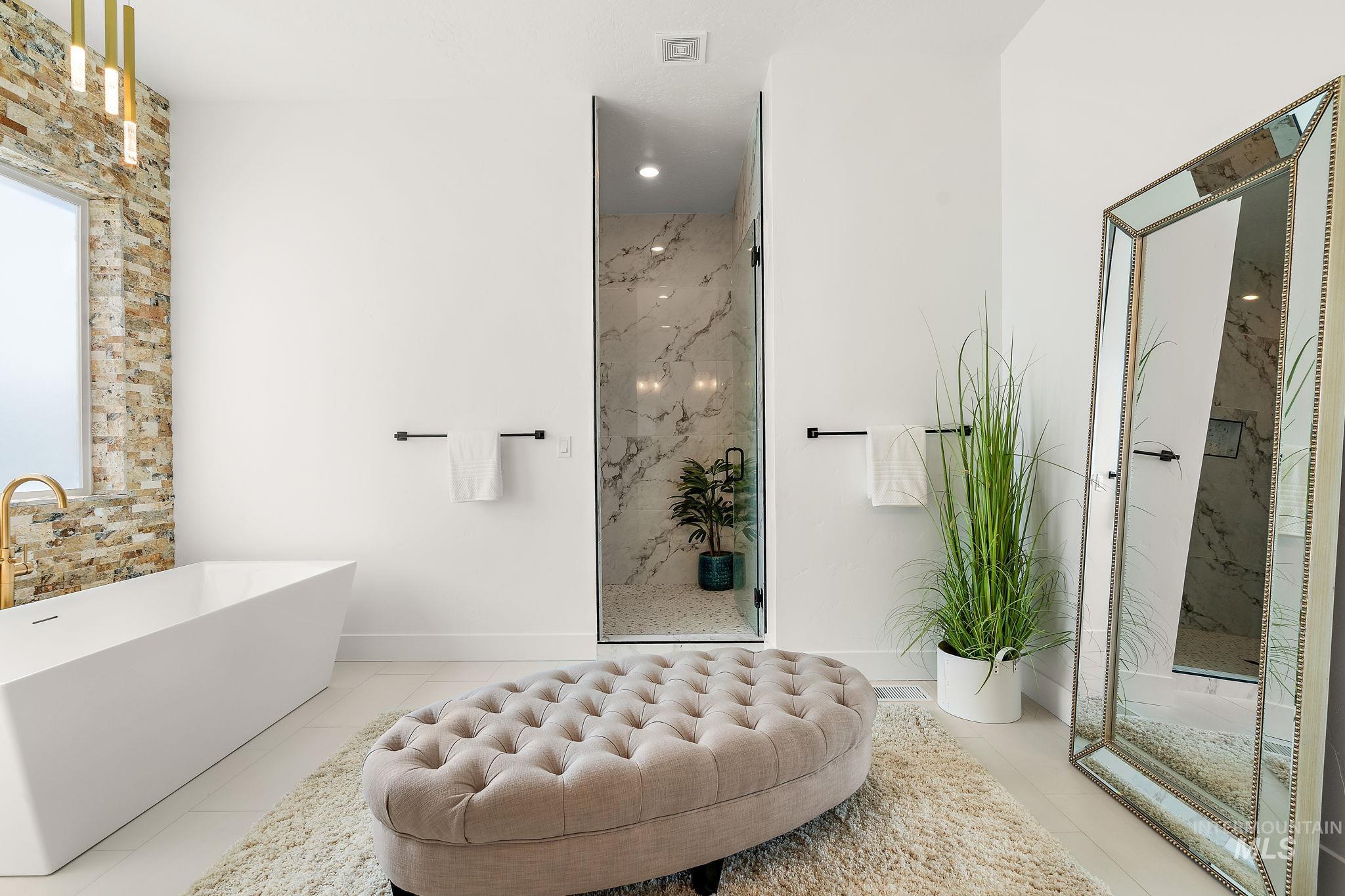 Bathroom with a marble finish shower and a freestanding tub