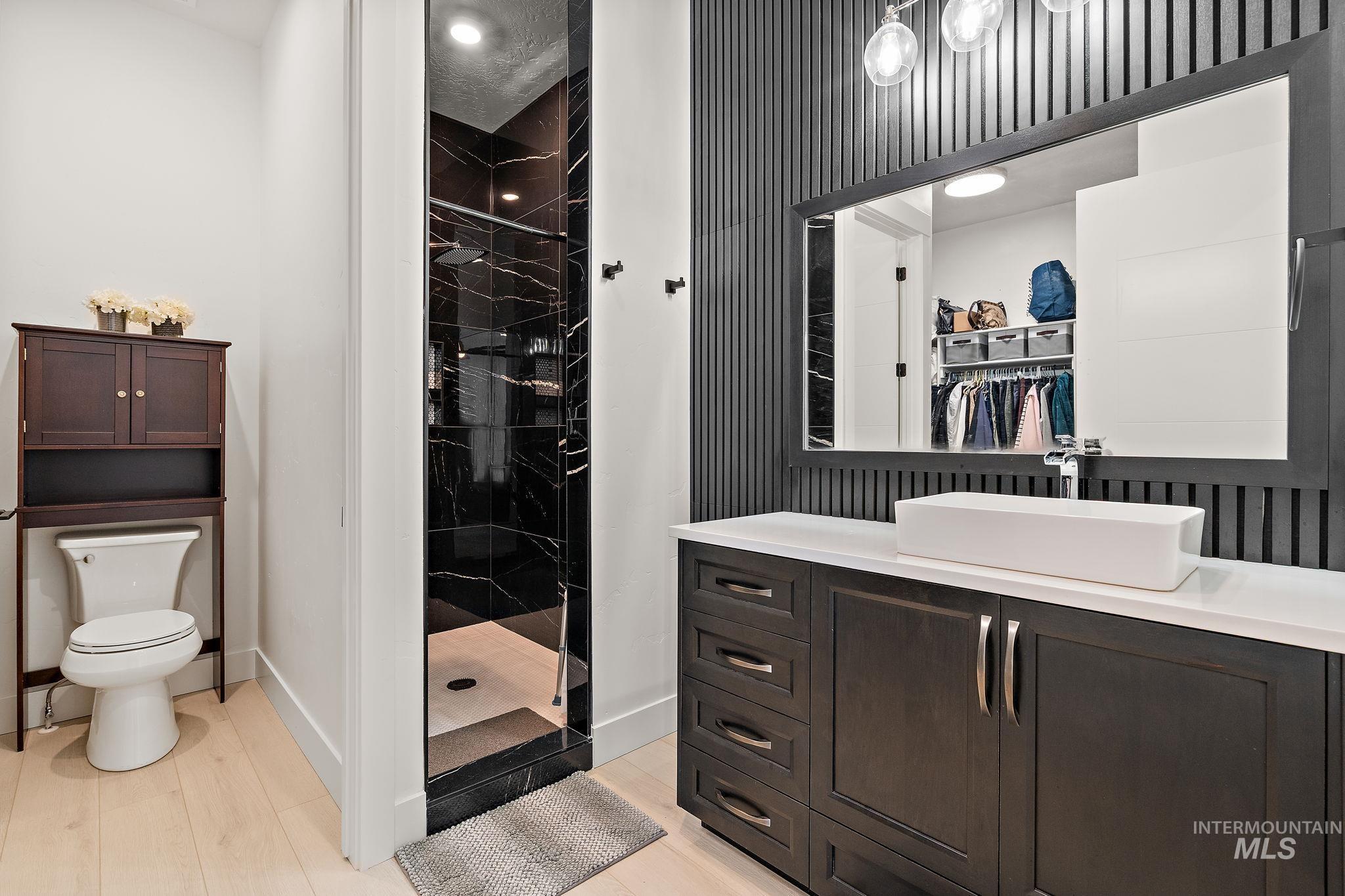 Bathroom with a spacious closet, a stall shower, vanity, light wood-type flooring, and recessed lighting