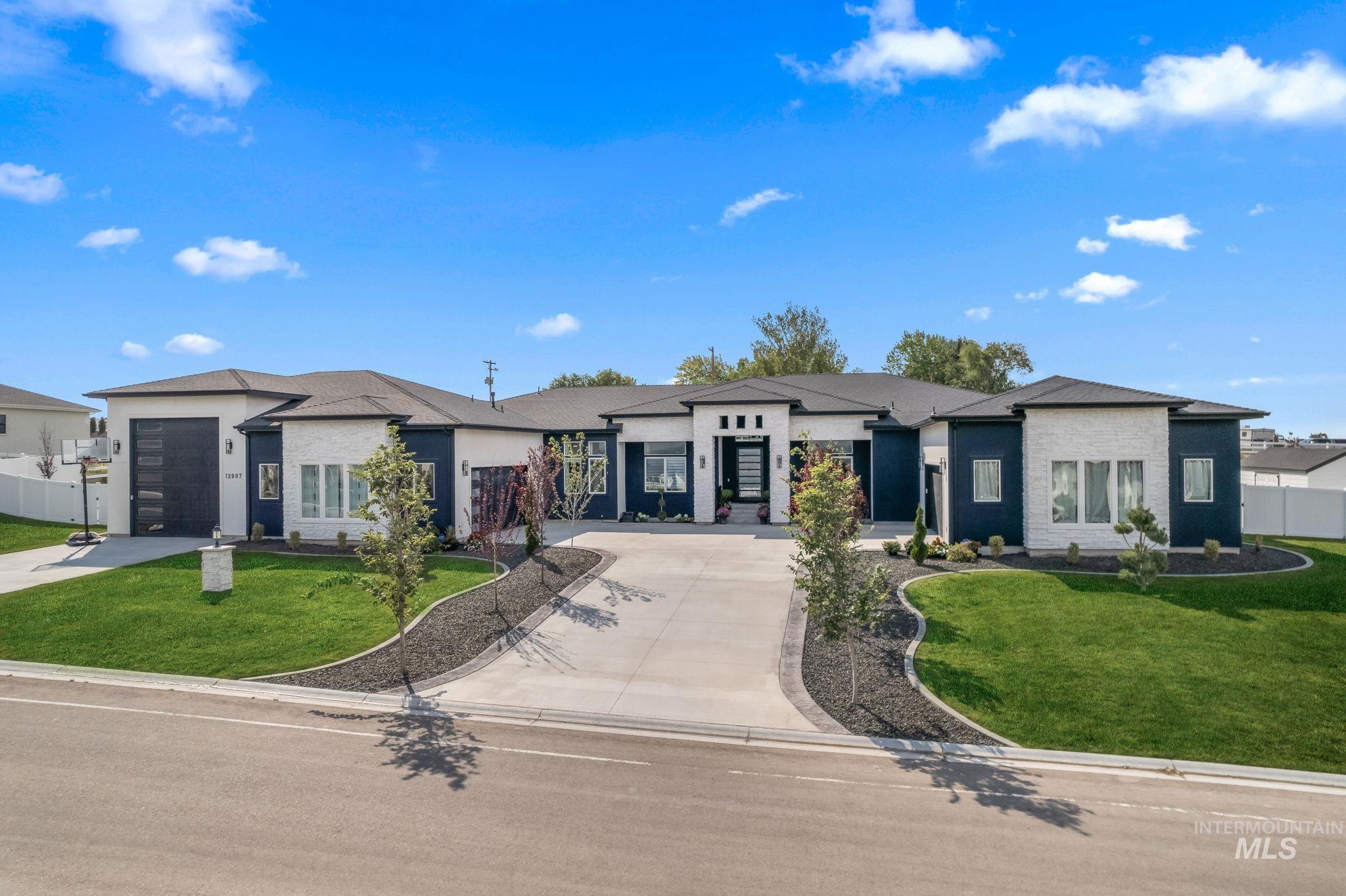 View of front facade featuring a front yard, concrete driveway, and an attached garage
