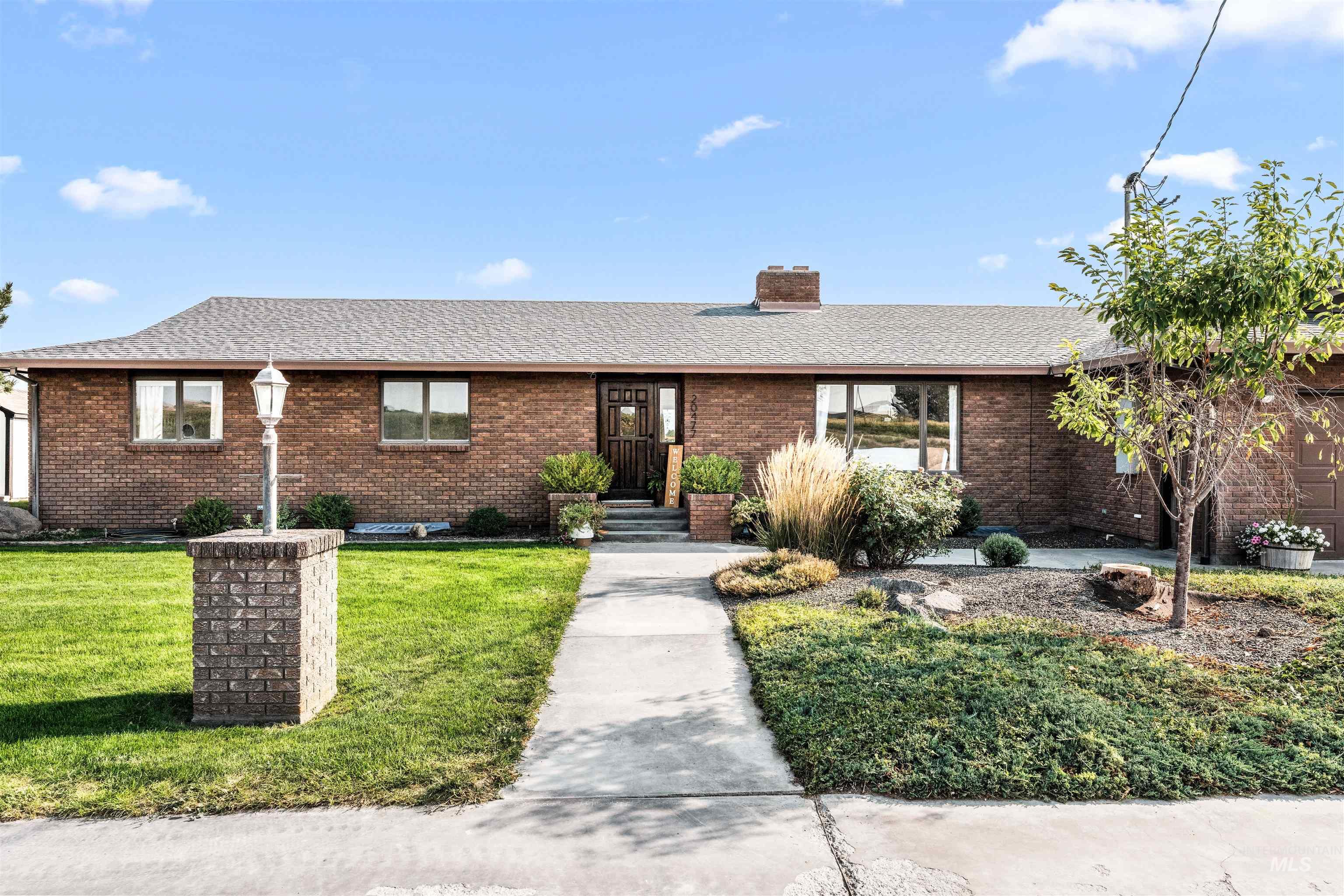 Ranch-style house featuring a shingled roof, brick siding, a chimney, and a front lawn