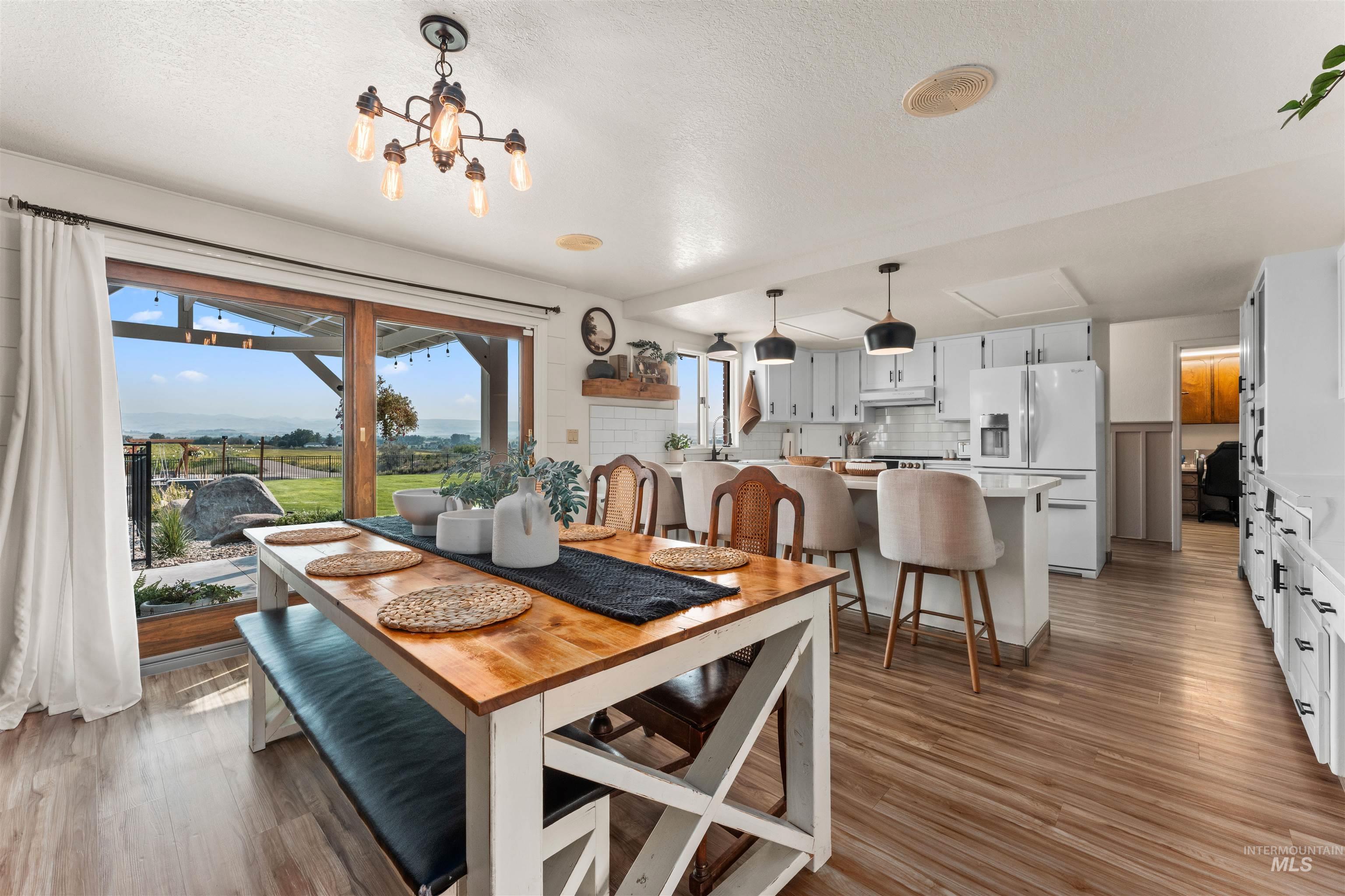 Dining area with dark wood-type flooring, plenty of natural light, a textured ceiling, and a chandelier