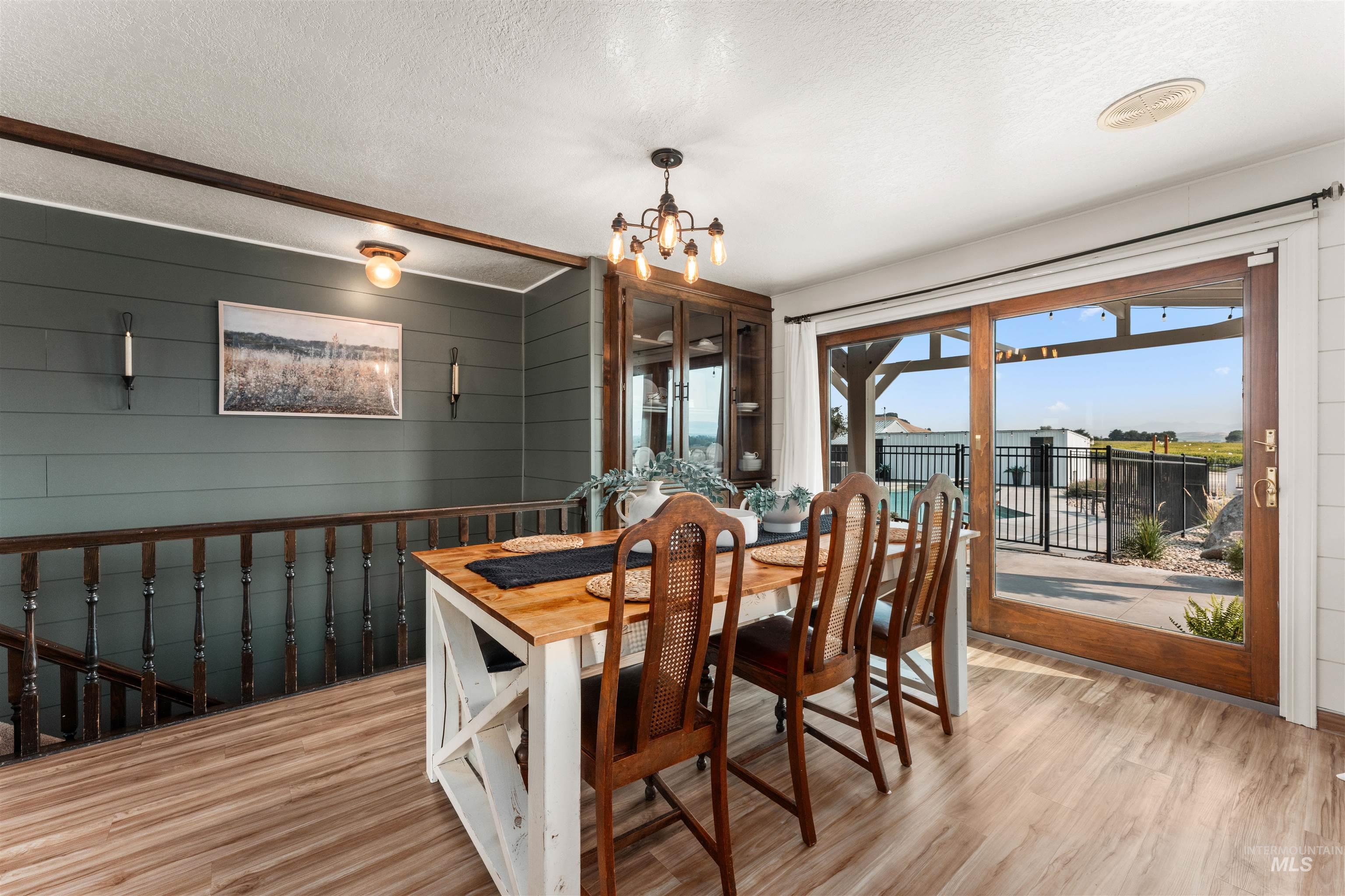 Dining space featuring wood walls, a textured ceiling, light wood-style flooring, and a chandelier
