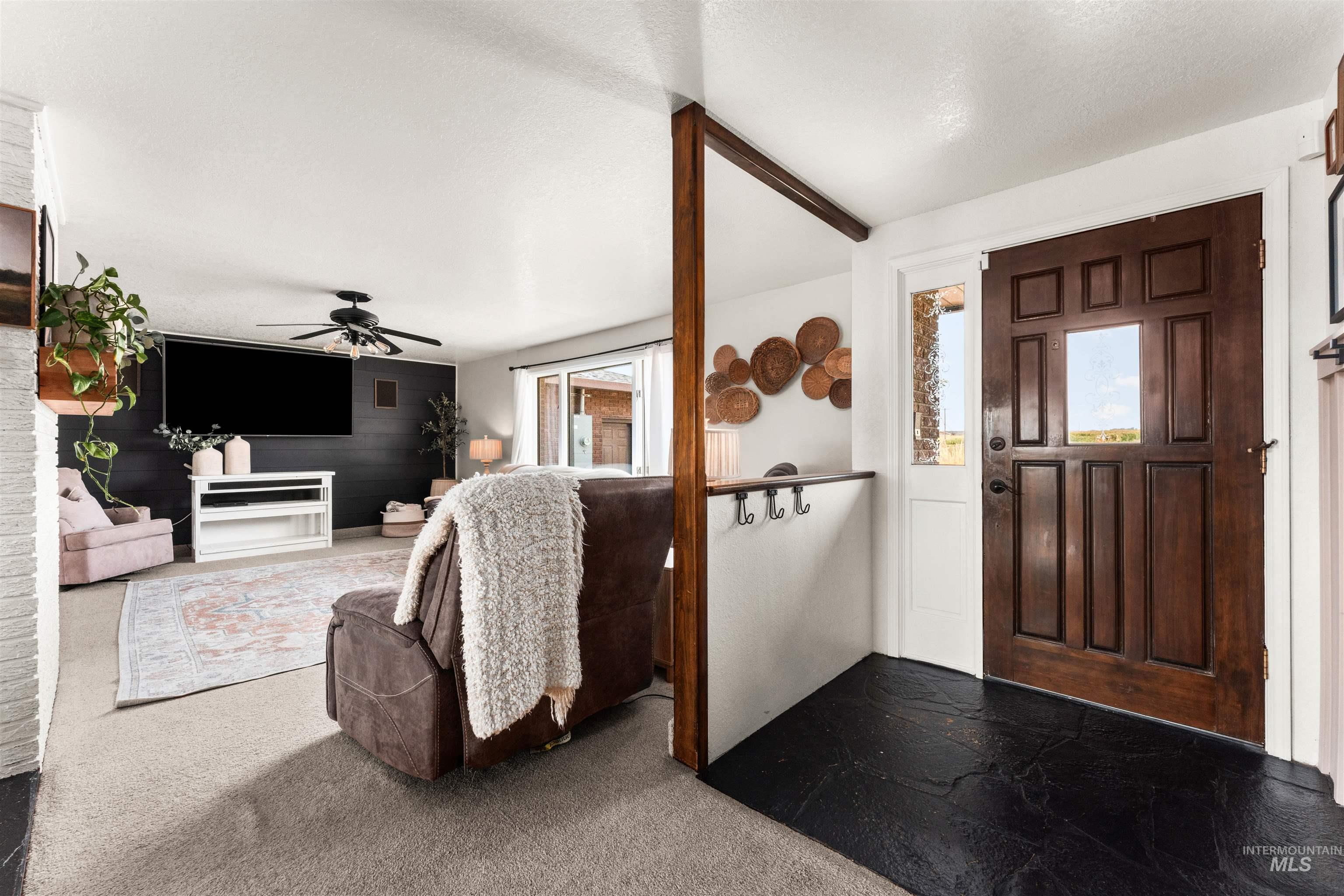 Carpeted foyer featuring ceiling fan and a textured ceiling