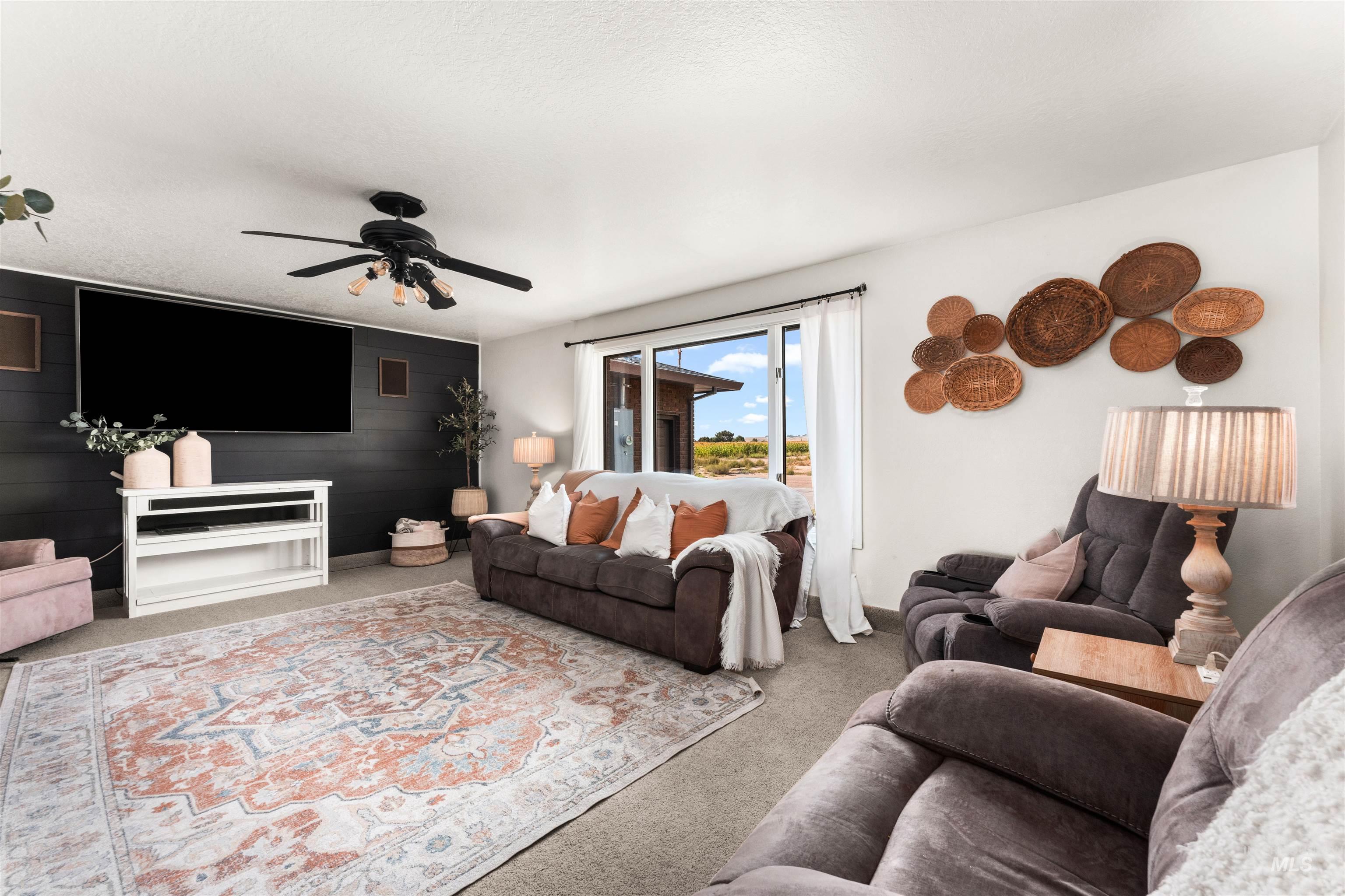 Living area with carpet, ceiling fan, and wood walls
