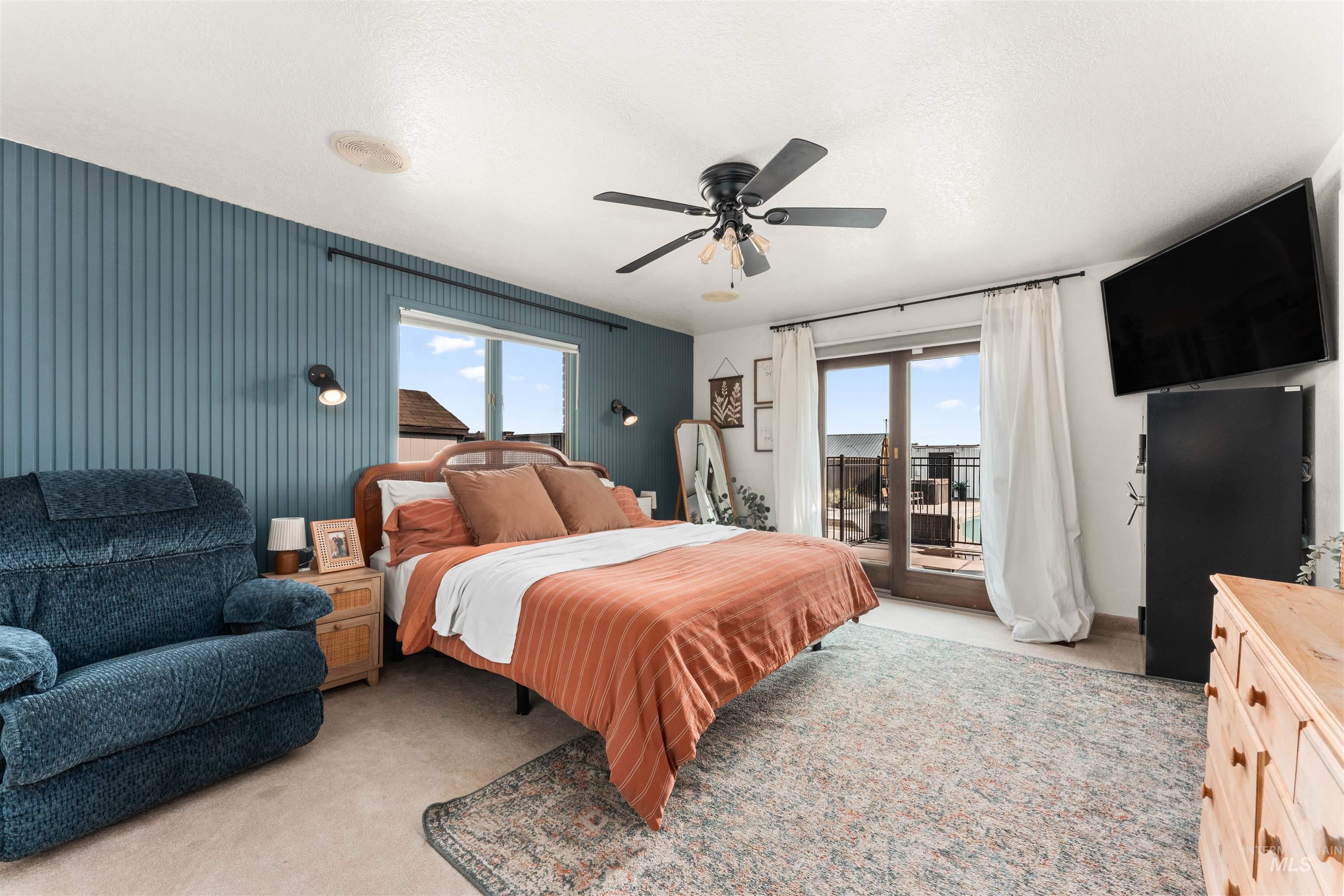 Bedroom featuring light carpet, access to exterior, ceiling fan, and a textured ceiling