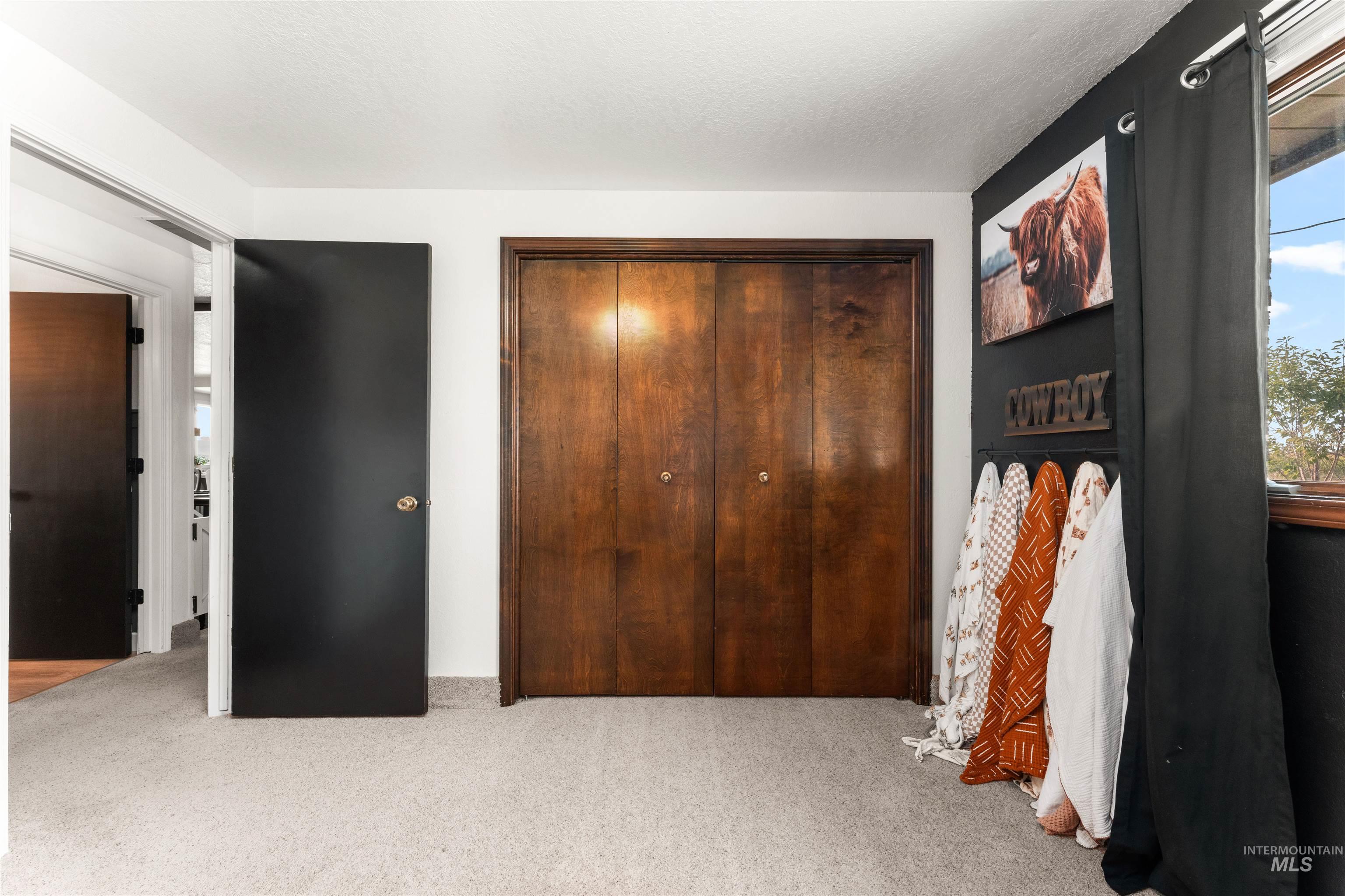 Bedroom with light carpet, a closet, and a textured ceiling