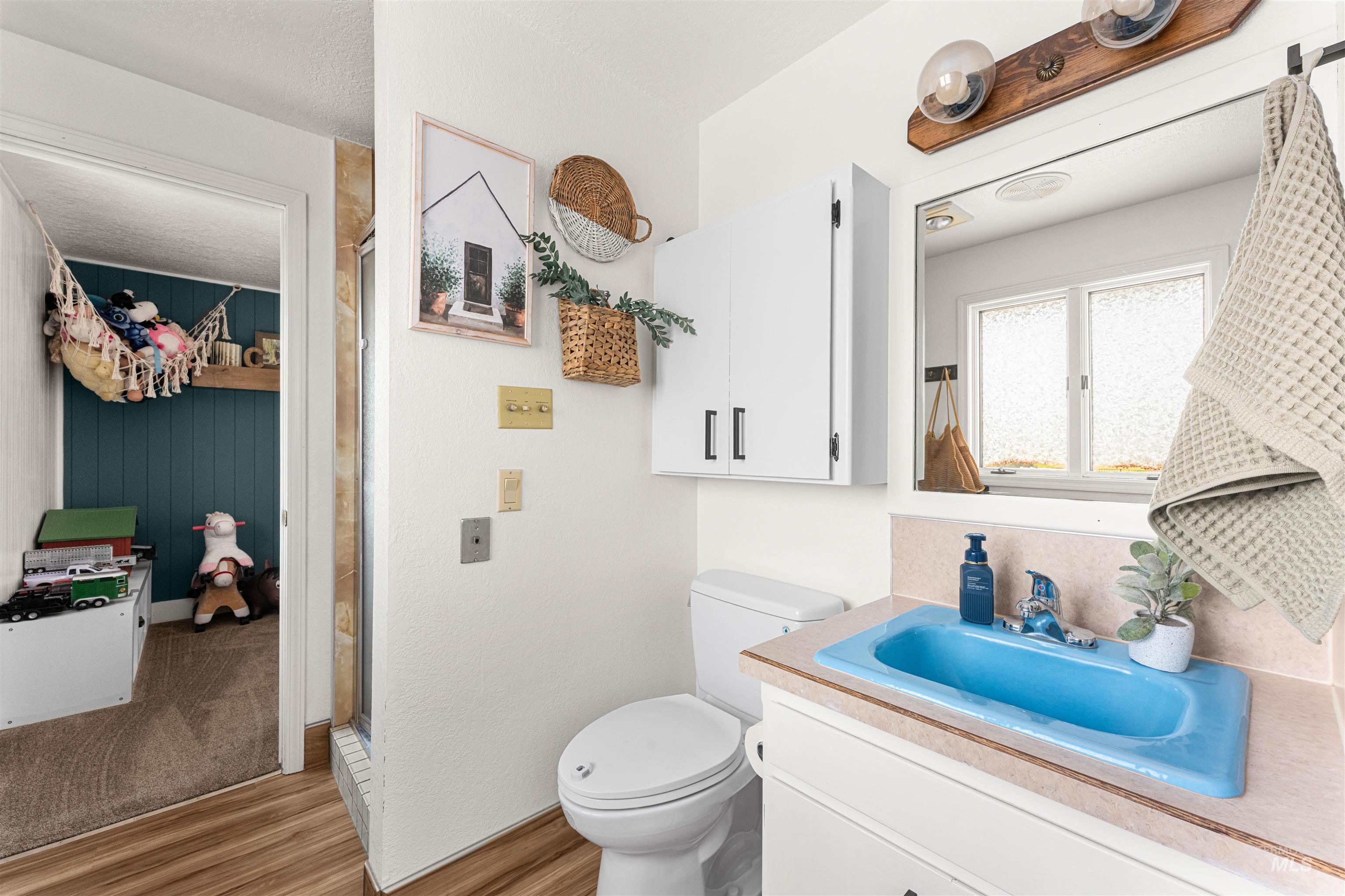 Bathroom featuring vanity, light wood-style flooring, a shower stall, and a textured ceiling