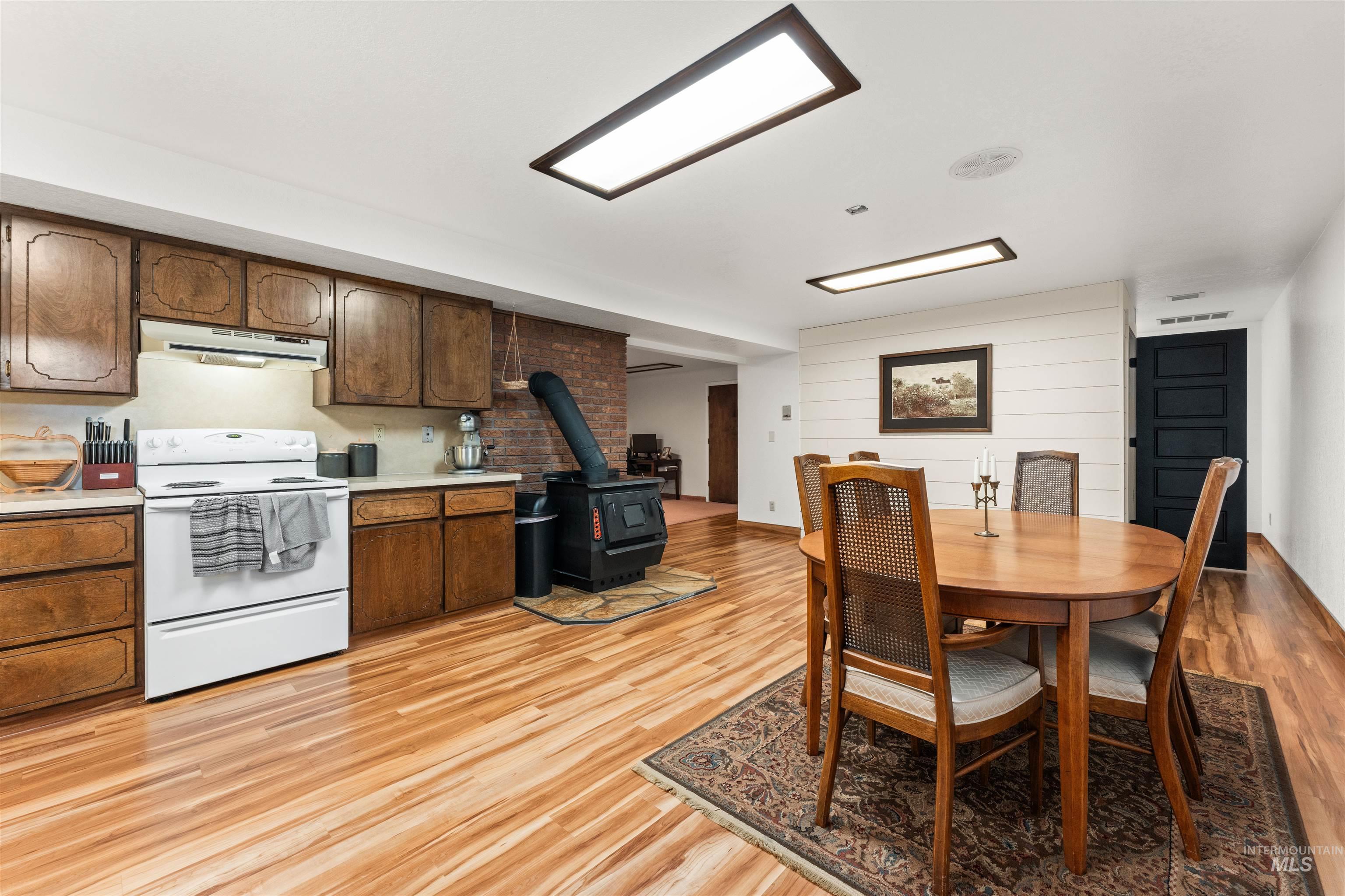 Dining space with a wood stove, light wood finished floors, and wooden walls