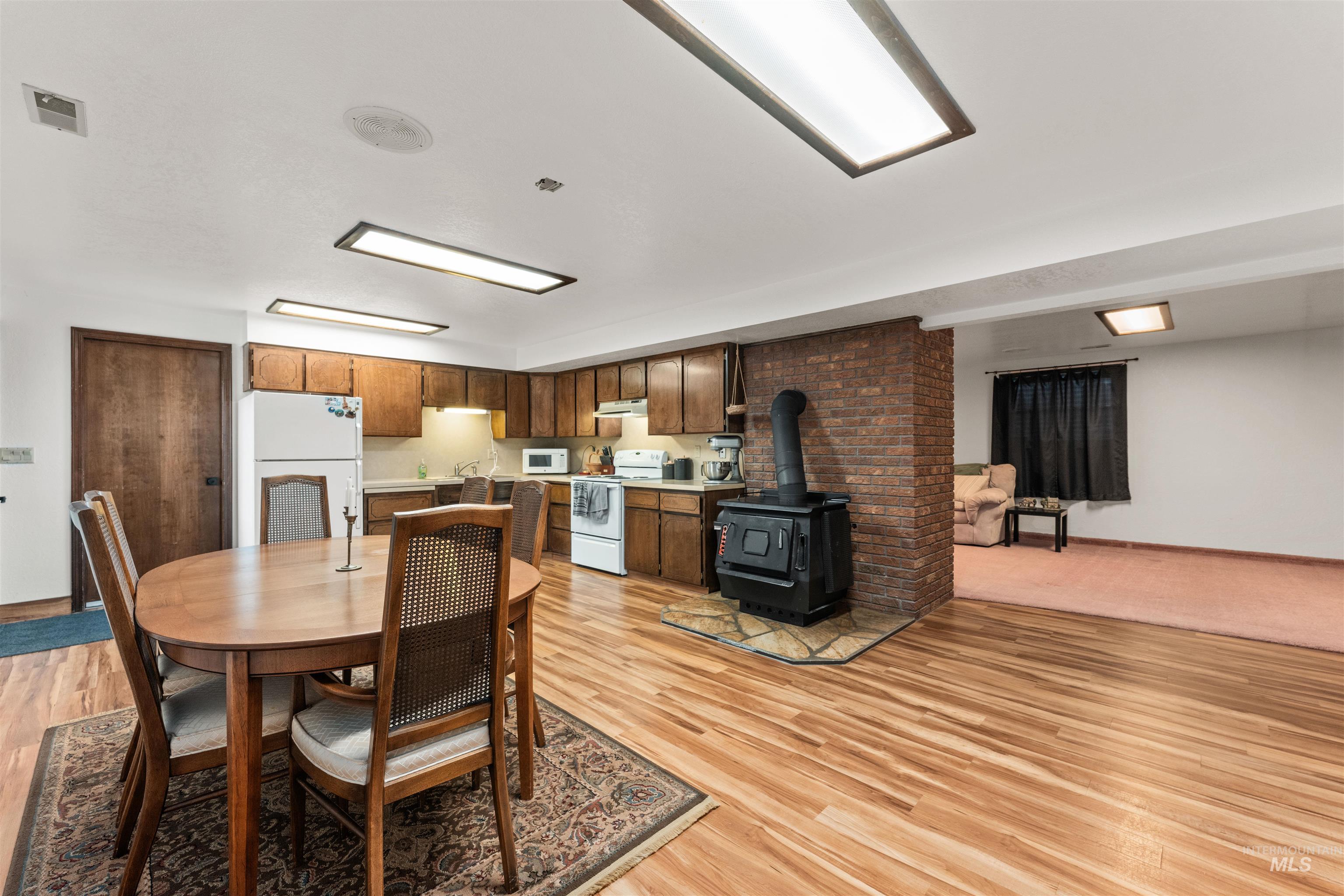 Dining area with a wood stove and light wood-type flooring