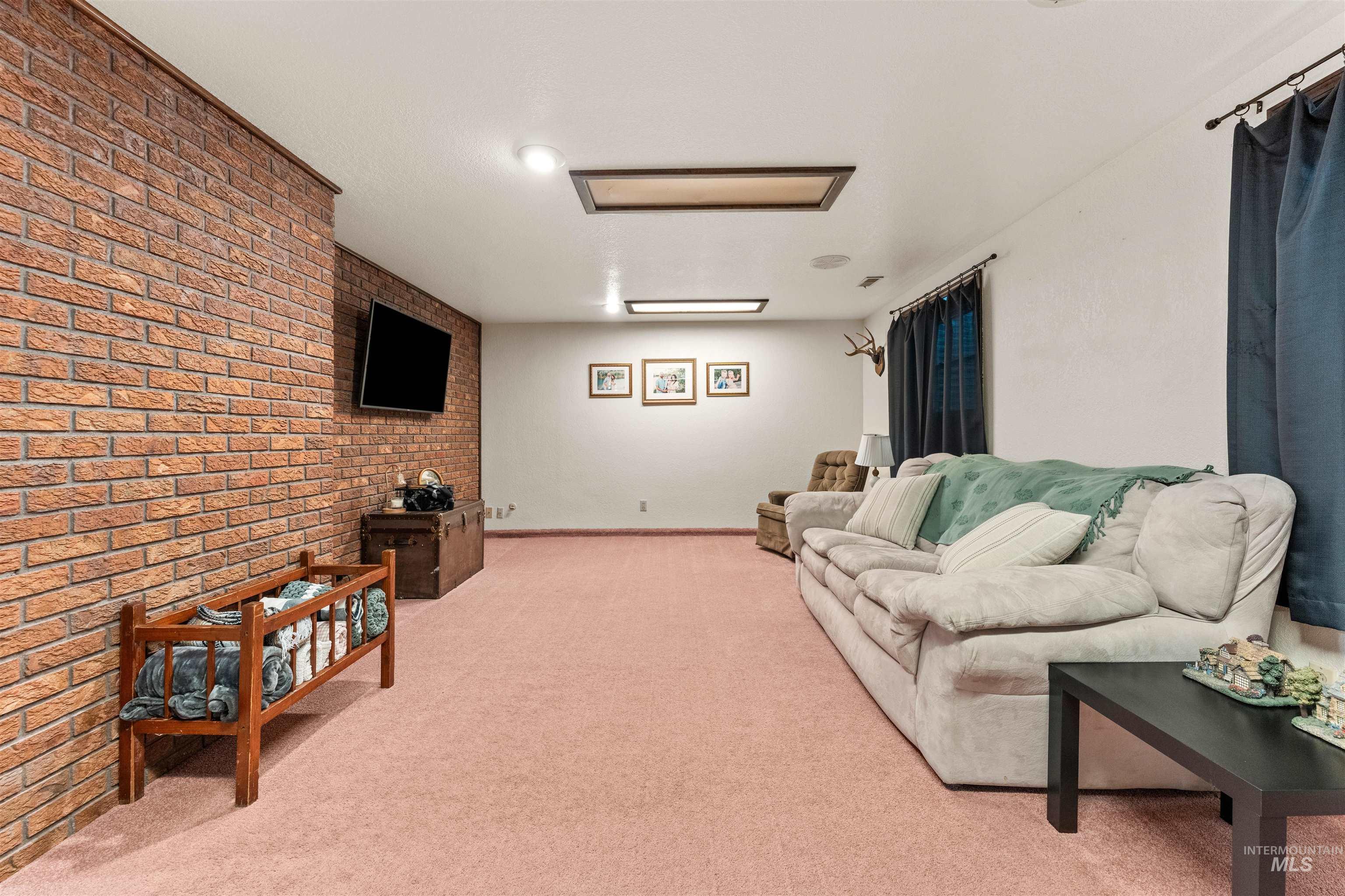 Living area featuring brick wall and light carpet