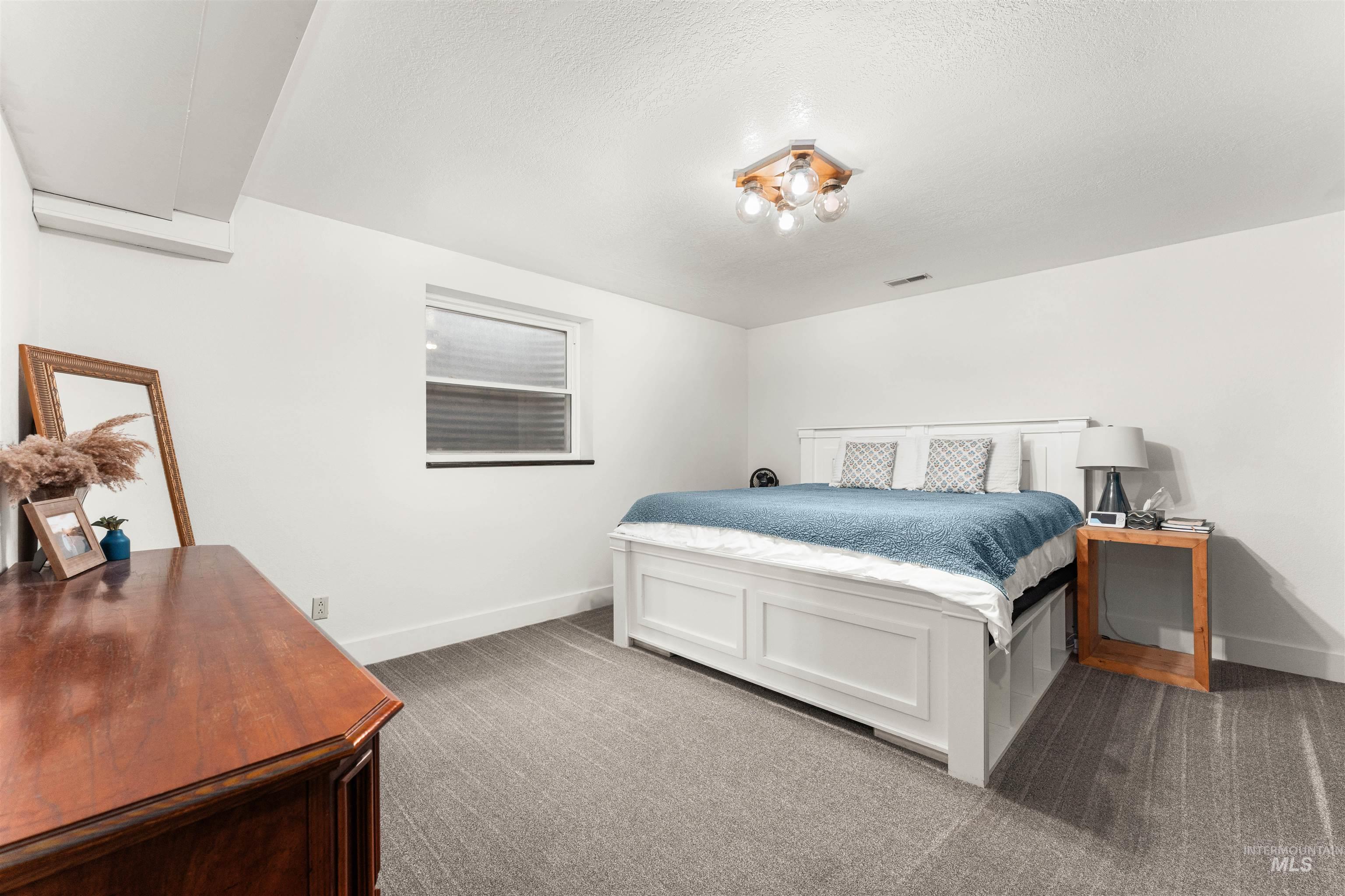 Bedroom with dark carpet and a textured ceiling
