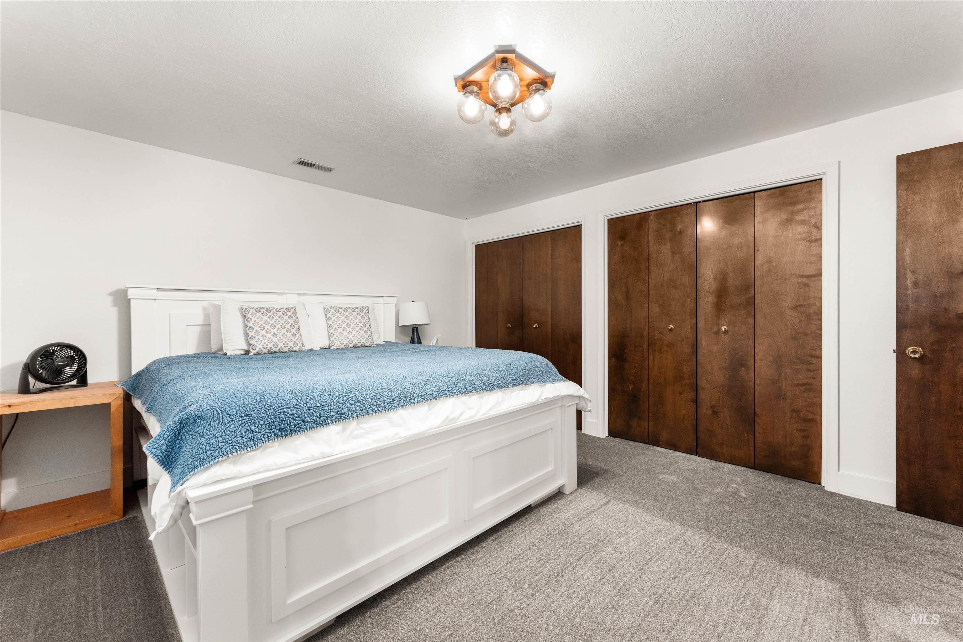 Carpeted bedroom featuring multiple closets and a textured ceiling