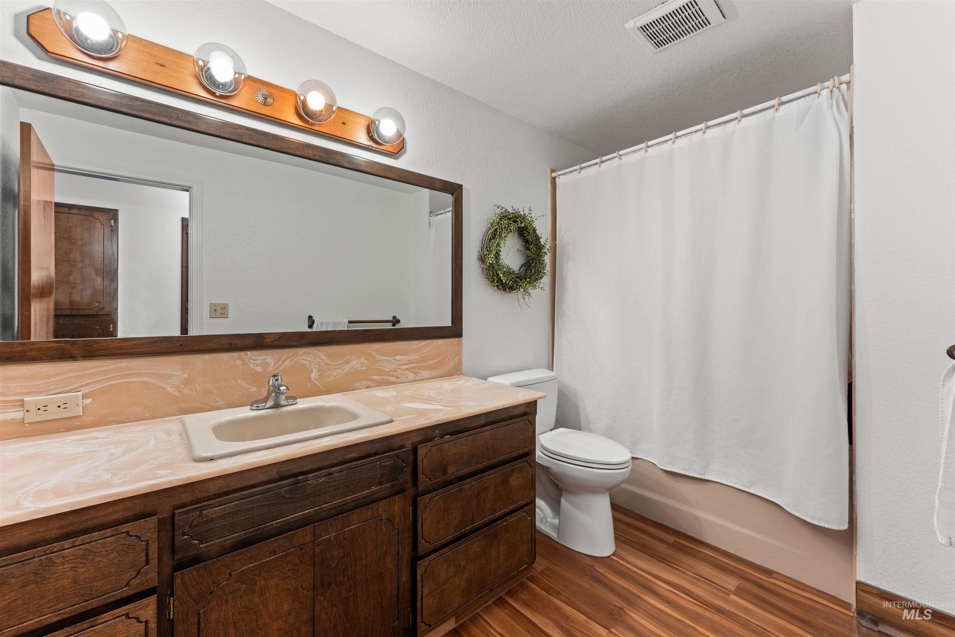 Full bath featuring vanity, dark wood-style floors, and shower / bath combo