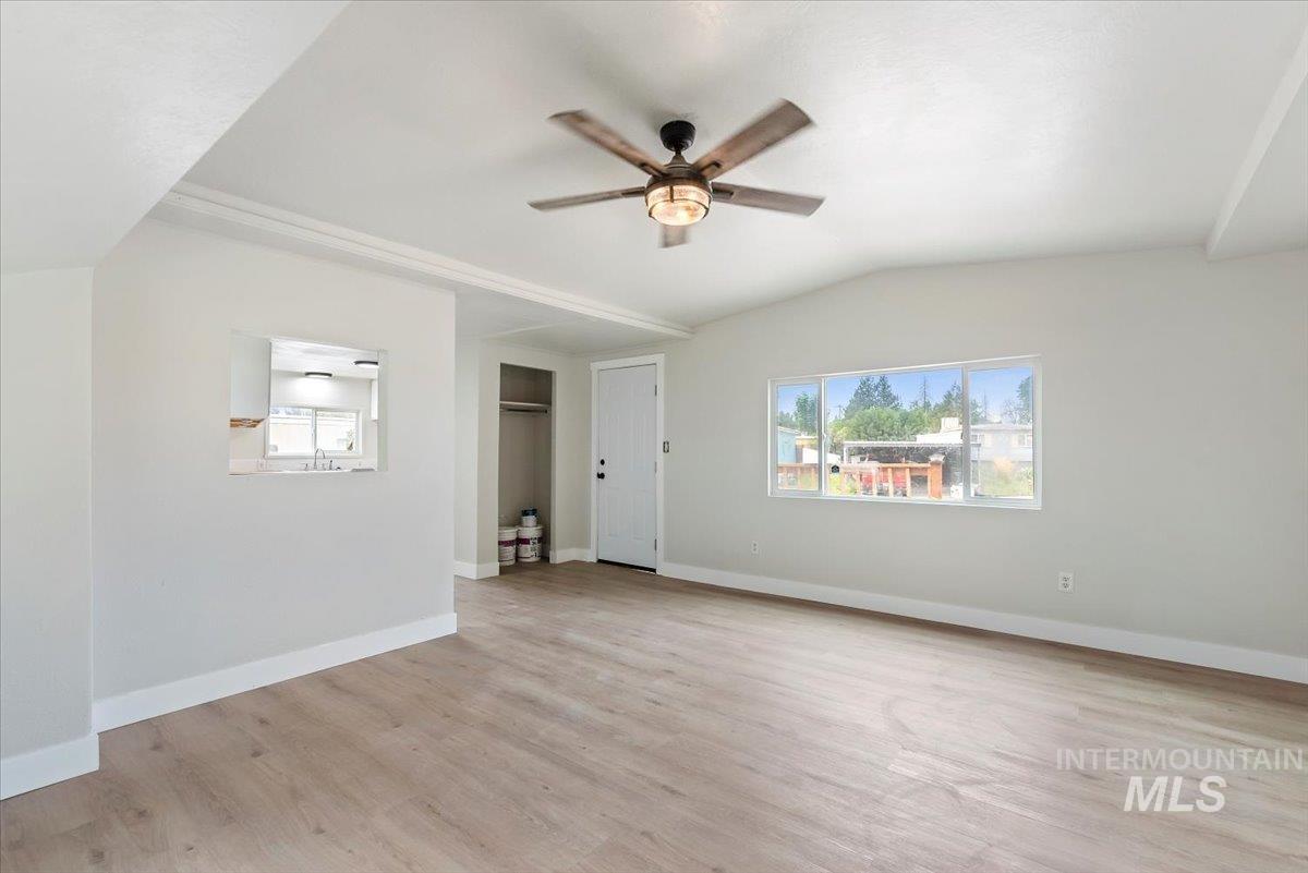 Unfurnished living room with light wood finished floors, lofted ceiling, and a ceiling fan